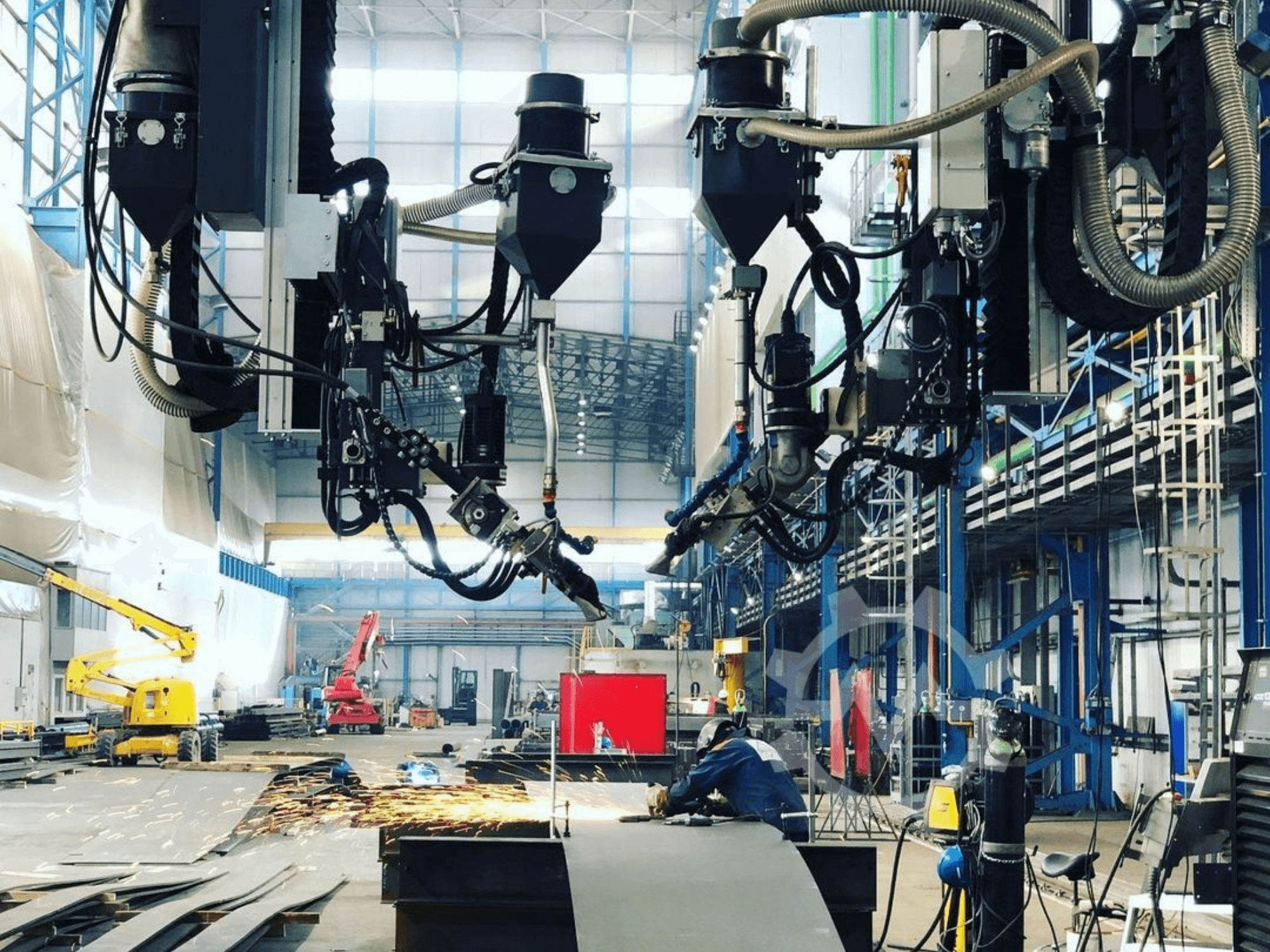 Machine à découper robotisée dans un environnement industriel, avec des étincelles, vue de côté ; elle comporte de nombreux accessoires et tuyaux.