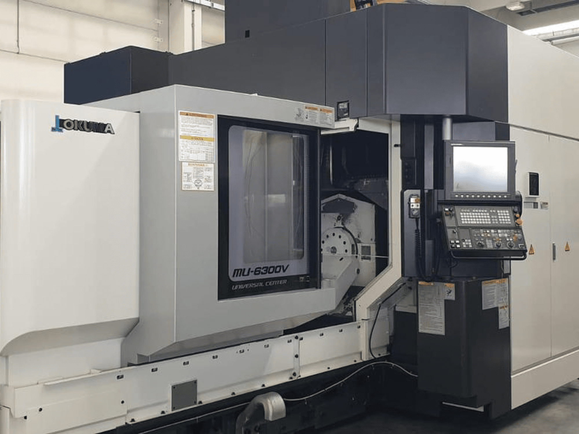 Centre d'usinage vertical Okuma MU 6300 V, vue de face présentant le panneau de commande et les détails de la zone d'usinage.