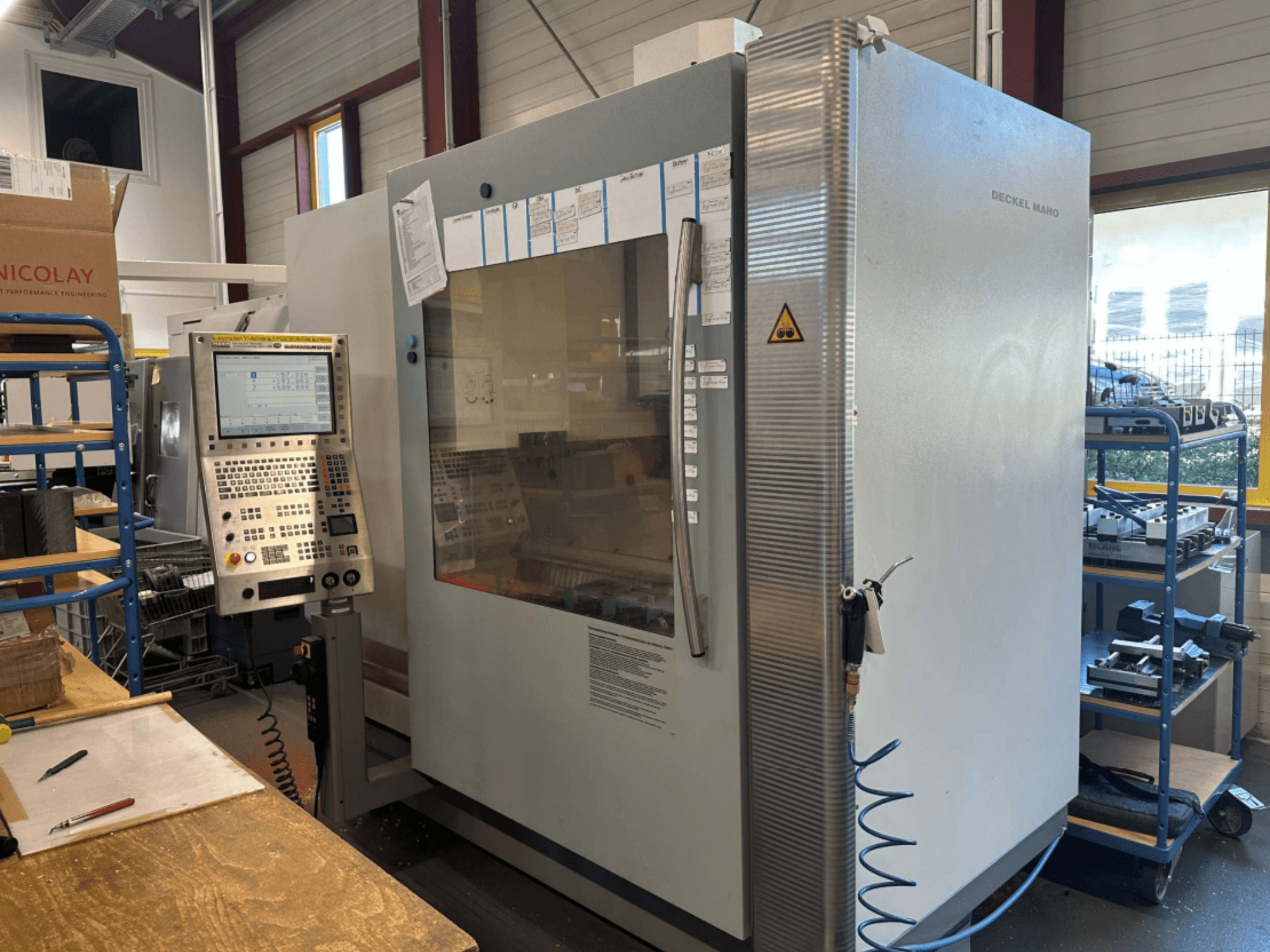 Centre d'usinage vertical DMG DECKEL MAHO 1035V, vue latérale montrant le panneau de commande et la structure de la machine, dans un atelier.