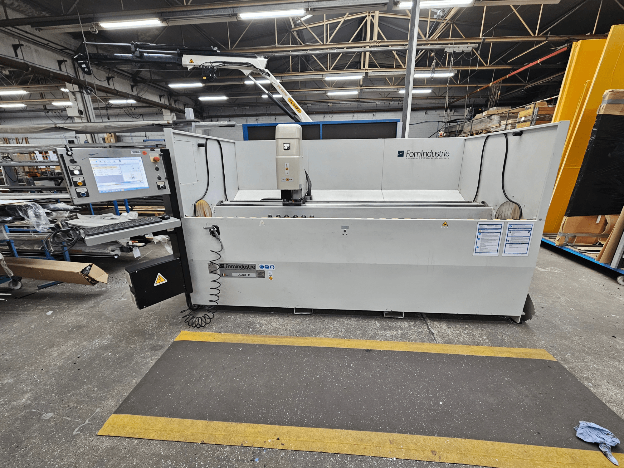 Centre d'usinage vertical ADIR C de FomIndustrie dans un atelier, vue de face montrant le panneau de commande et les détails de la machine.