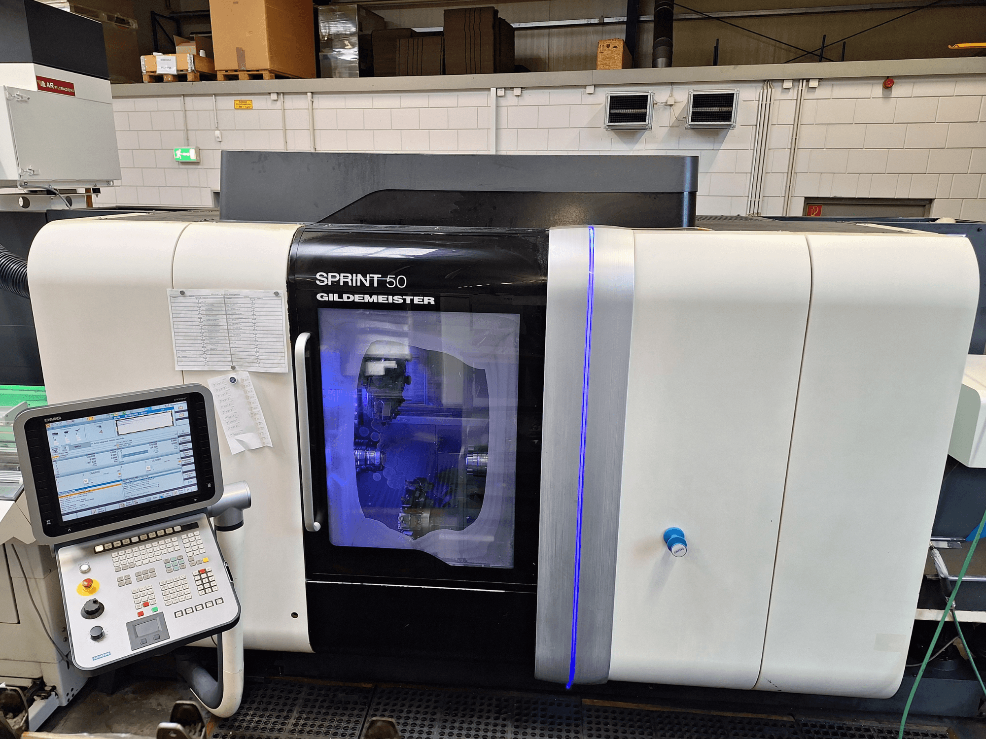 Tour horizontal DMG Sprint 50 2T, vue de face, avec panneau de commande et carter transparent présentant les machines à l'intérieur.