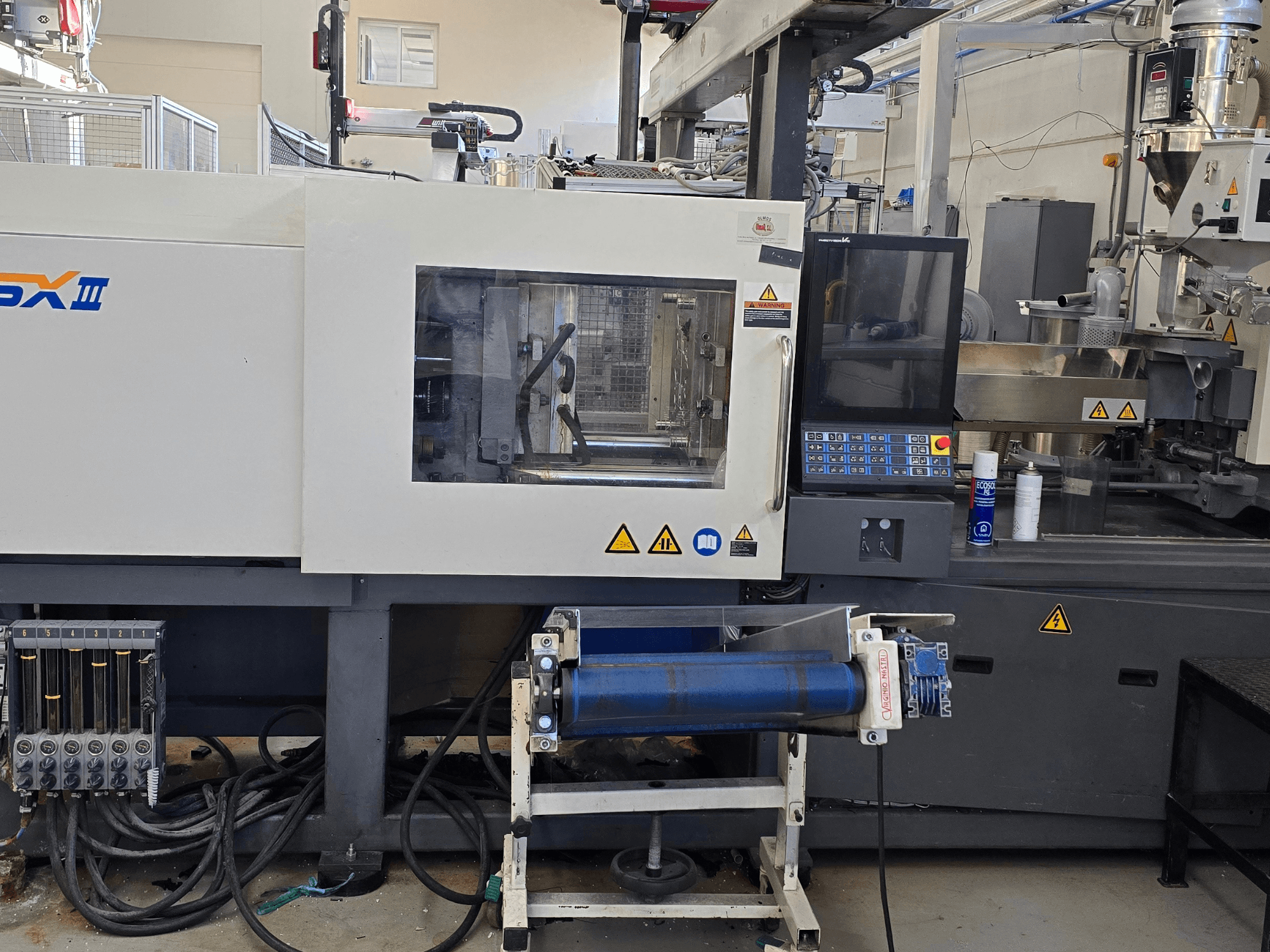 Machine de moulage par injection électrique SHIBAURA EC130SXIII-4A, vue de face, présentant le panneau de commande et les composants hydrauliques.