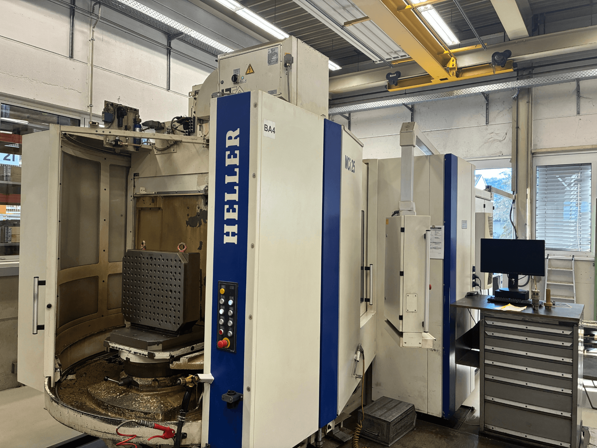 Centre d'usinage horizontal HELLER MCi 25, vue de face ; la table de travail est équipée d'un dispositif hexagonal et le panneau de commande est visible.