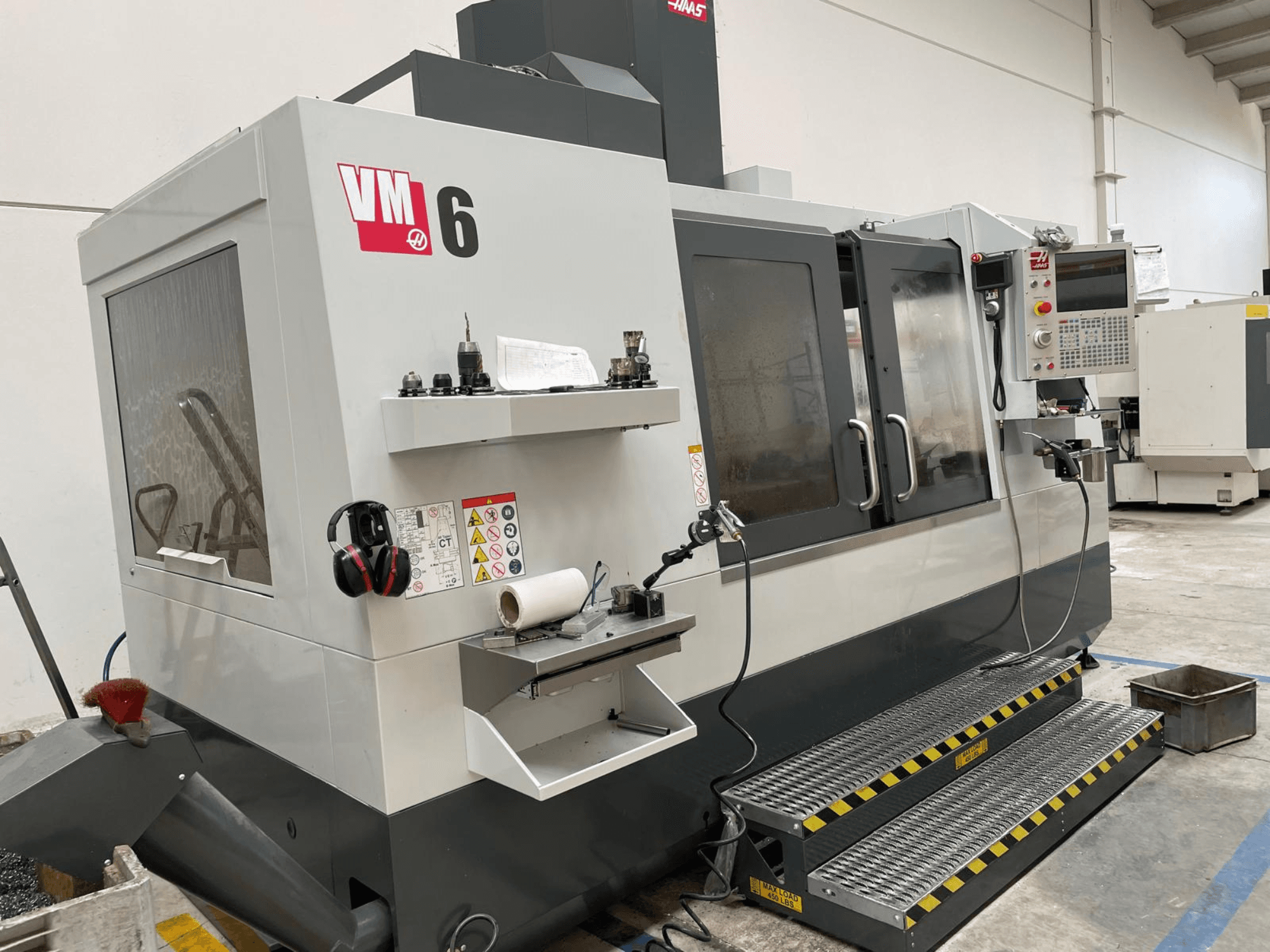 Centre d'usinage vertical Haas VM-6, vue de face montrant le panneau de commande, les porte-outils et les dispositifs de sécurité.