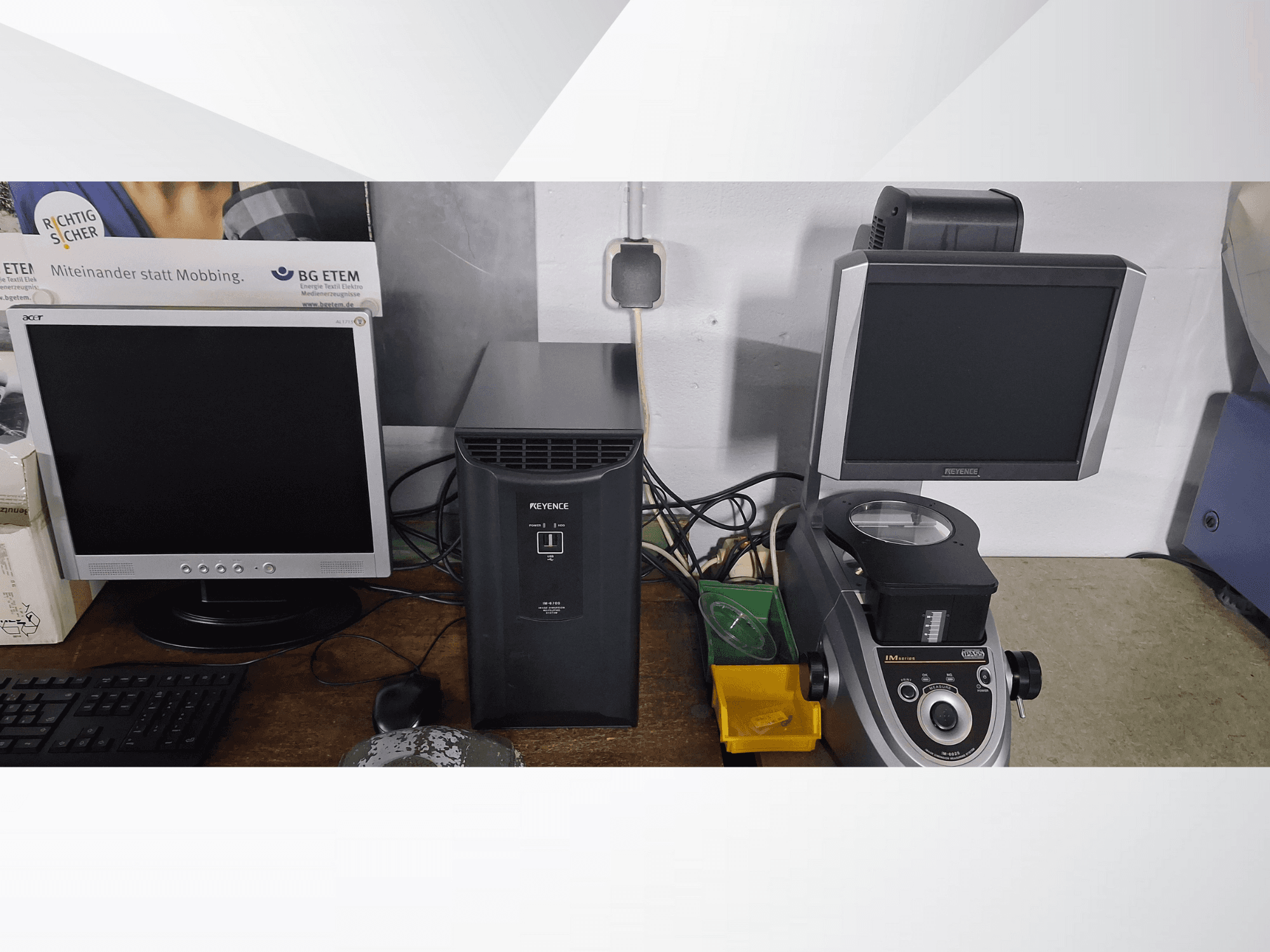 Deux écrans d'ordinateur, un Acer et un Keyence, à côté d'un dispositif noir et d'un microscope, vus de face.