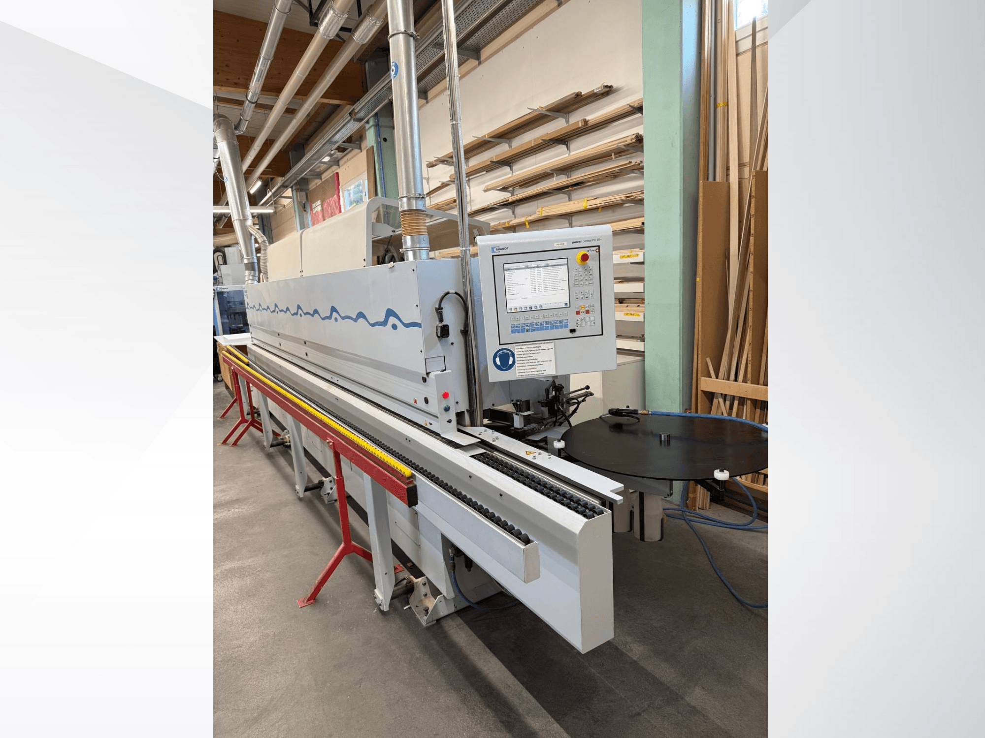 Vue de face d'une plaqueuse de chants automatique HolzHer avec un panneau de commande, un système de transport et une table de support ronde.