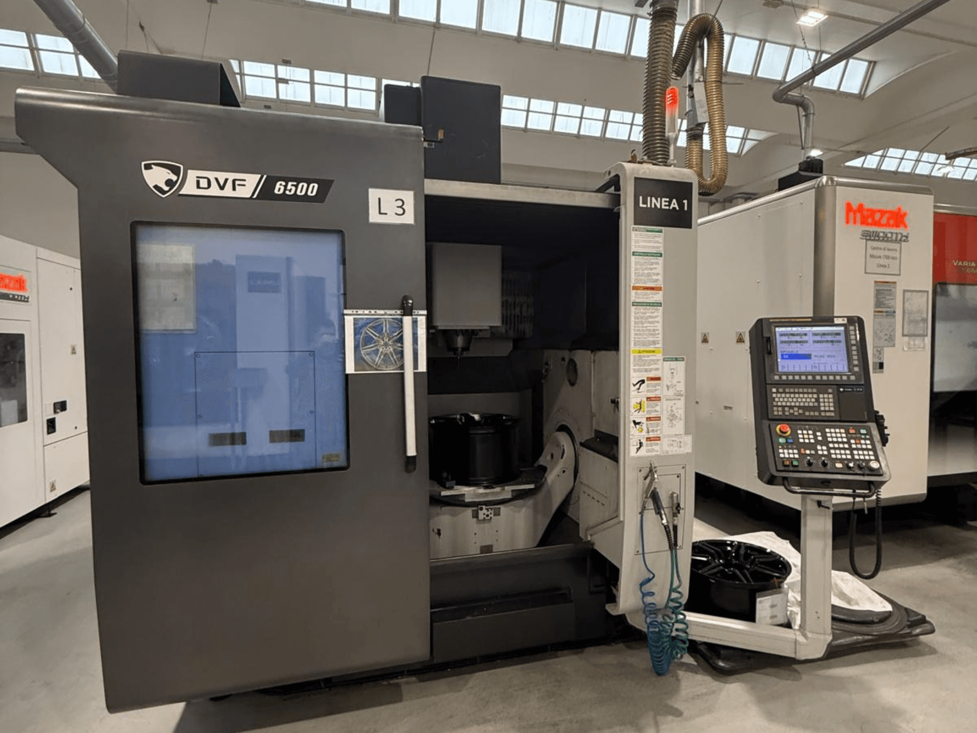 Machine CNC DVF 6500, vue de face, montrant le panneau de commande et l'espace intérieur avec un dispositif de fixation de pièce.