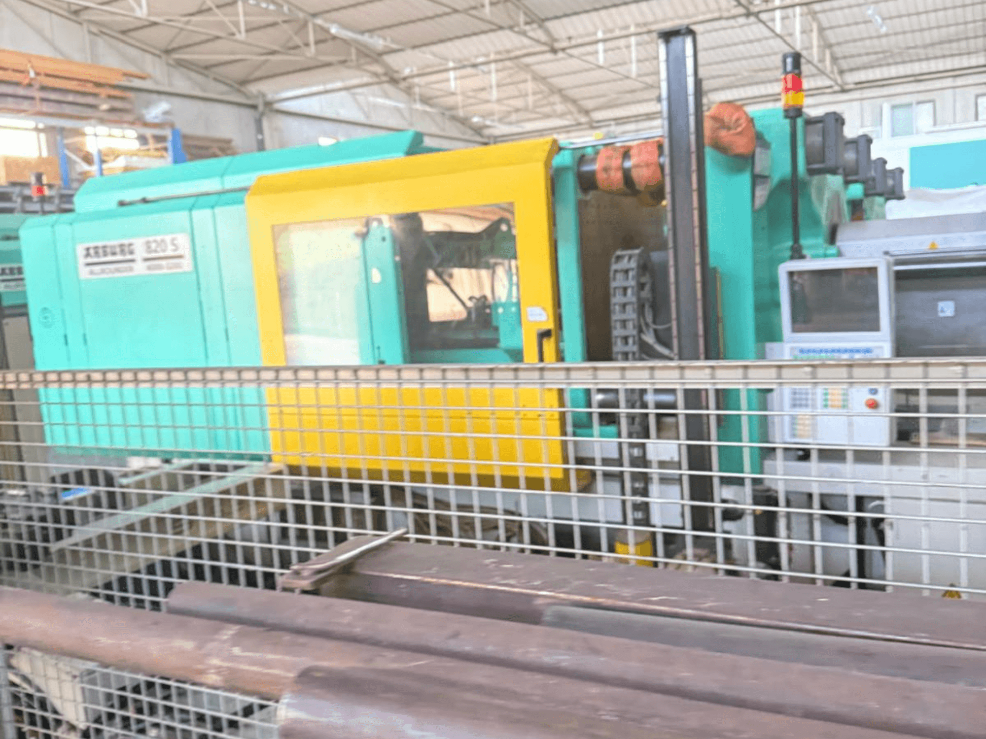 Machine de moulage par injection hydraulique Arburg SELECTA 820 S 4000-3200, vue de côté, montrant le panneau de commande et le design jaune et sarcelle éclatant.