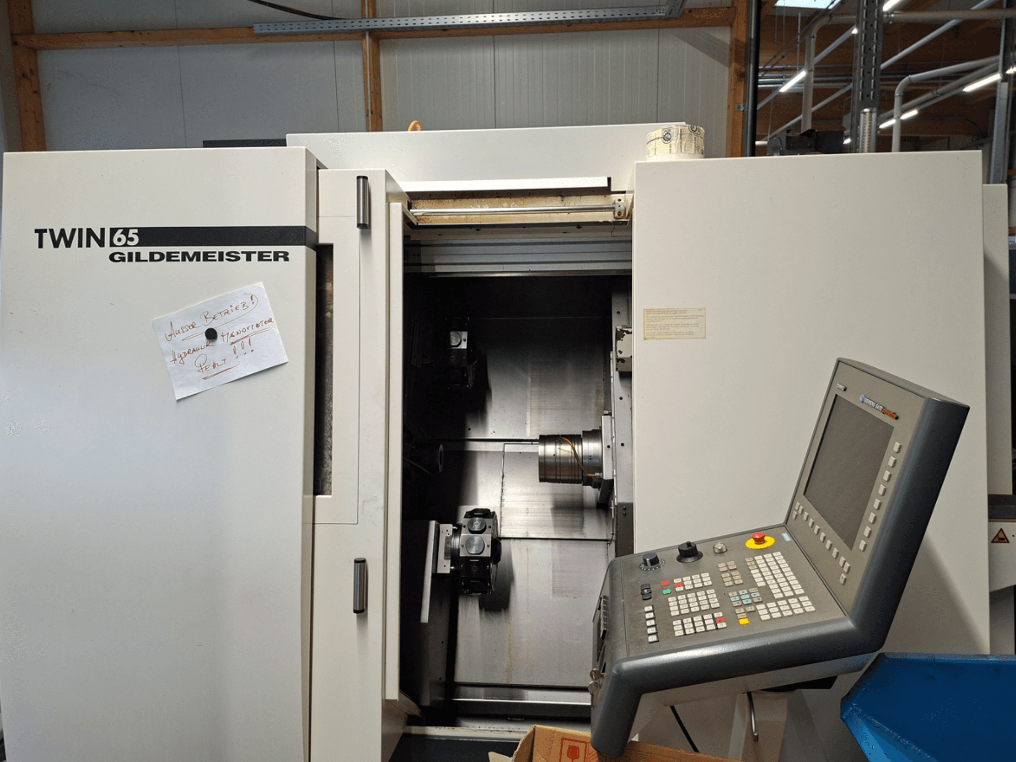 Tour CNC Gildemeister TWIN 65, vue de face montrant le panneau de commande et la chambre partiellement ouverte avec les machines visibles.