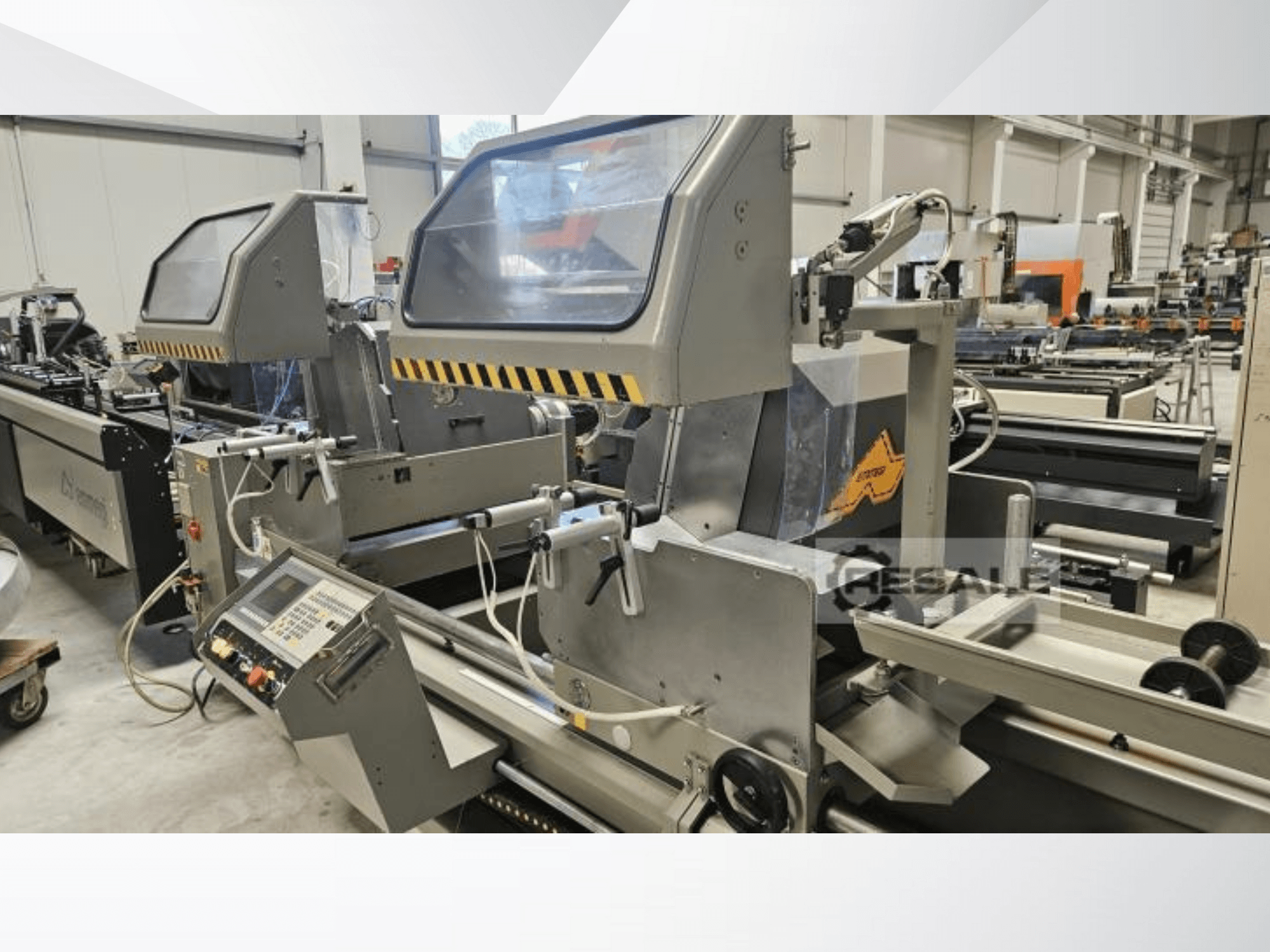 Machines à scier doubles dans une usine ; vue de face montrant le panneau de commande, les couvercles en verre et les éléments de coupe.