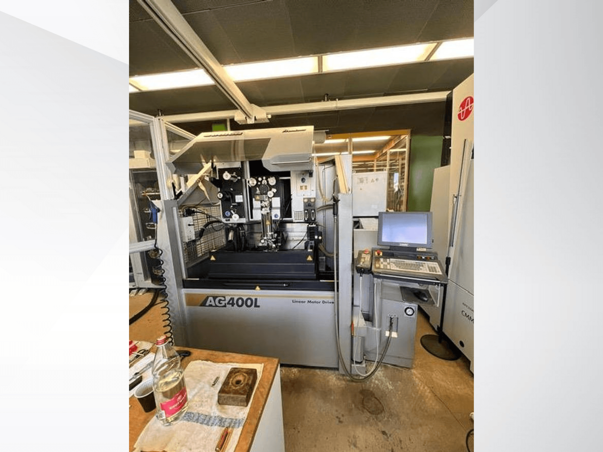 Machine à entraînement par moteur linéaire AG400L, vue de face, avec le panneau de commande et la zone de travail, avec les dispositifs de sécurité visibles.