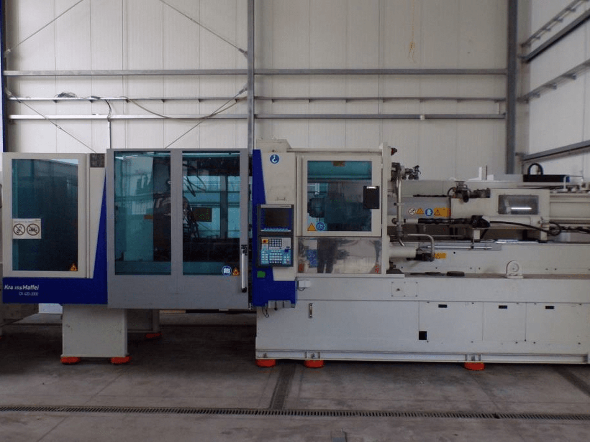 Machine de moulage par injection KraussMaffei, vue de côté, avec panneau de commande et indicateurs de sécurité, visible en usine.