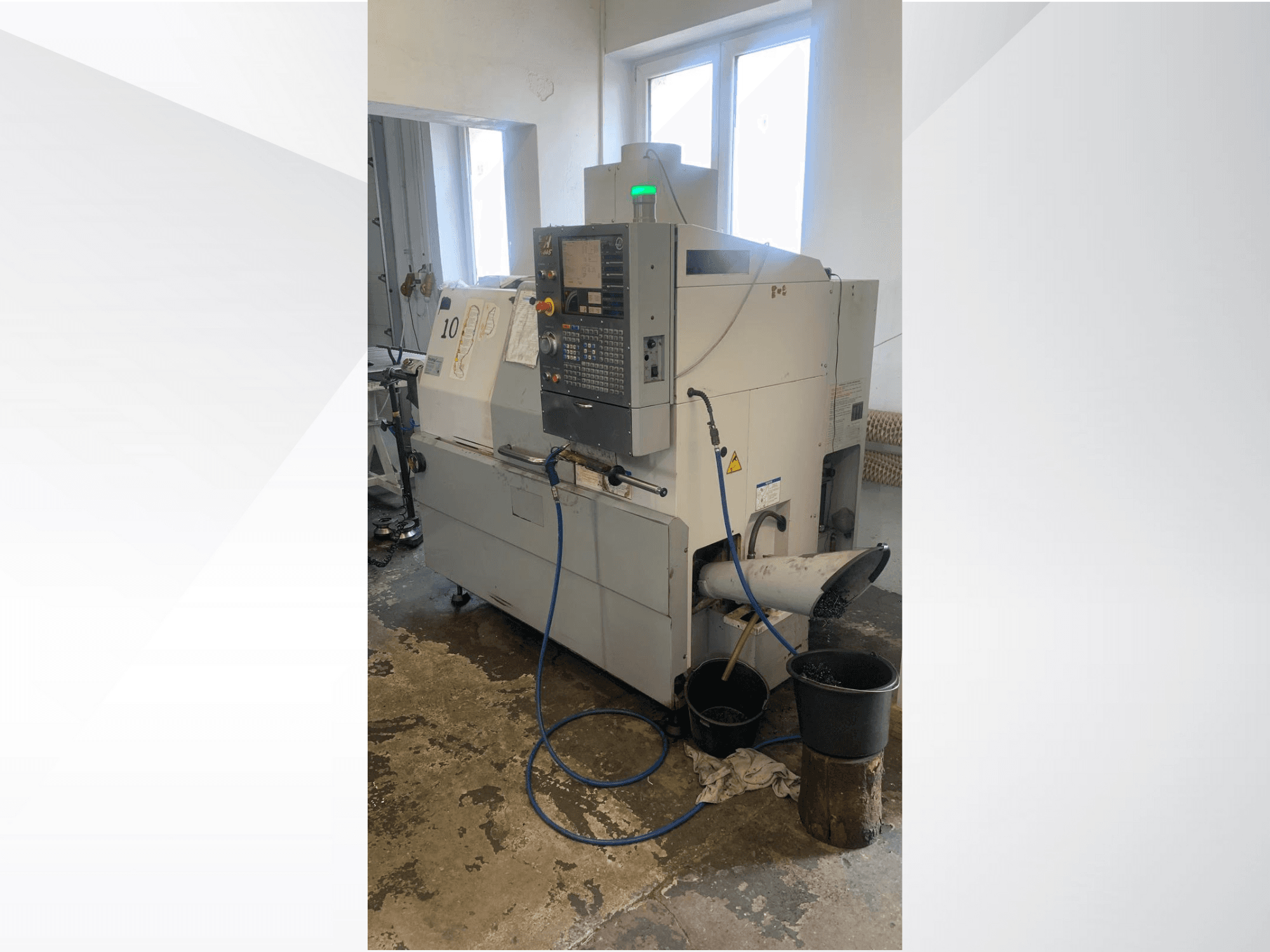 Modèle de machine CNC Haas avec panneau de commande, vue latérale, comprenant la ligne de refroidissement, la goulotte de déchets et les conteneurs de stockage situés en dessous.