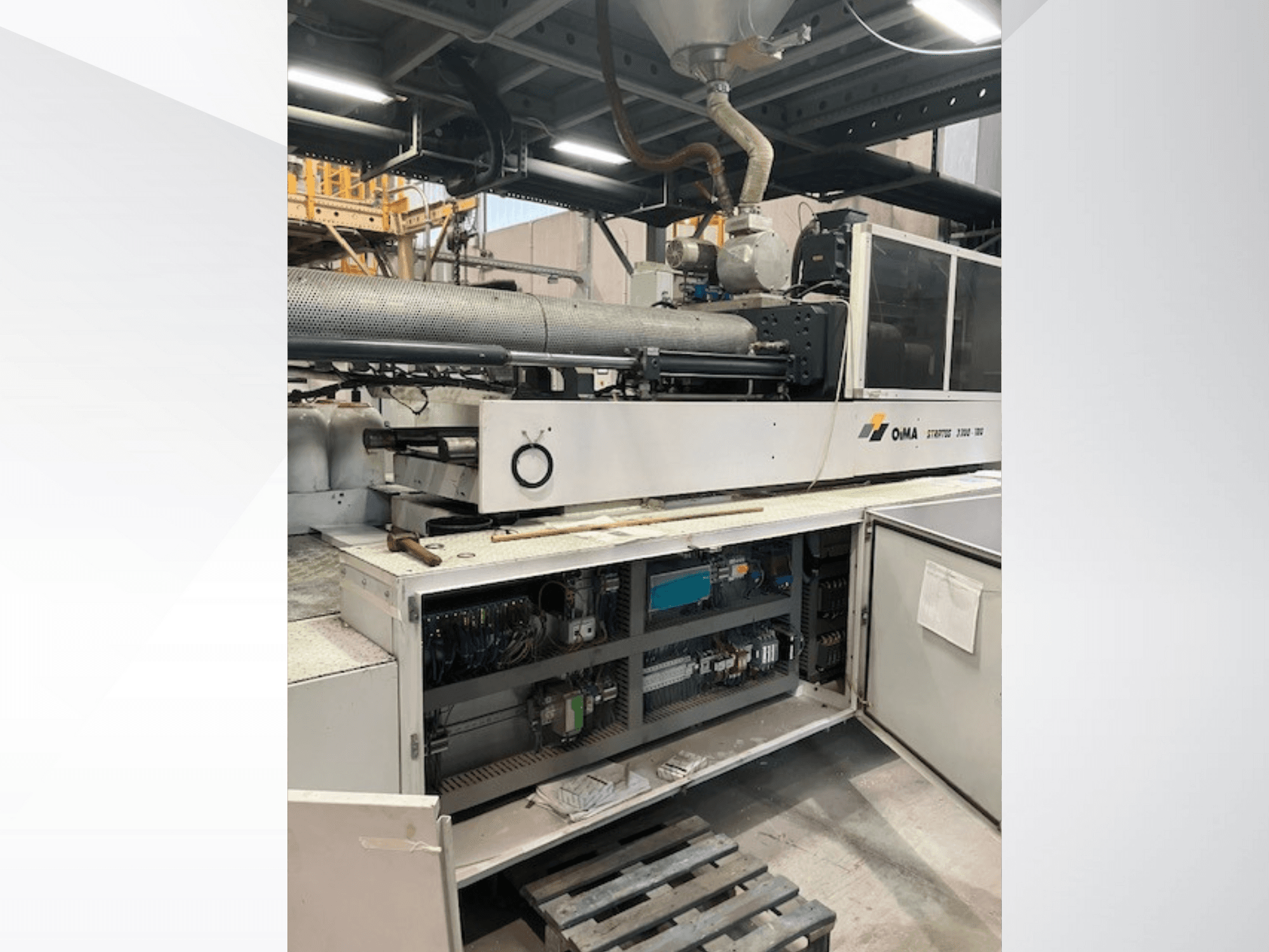 Vue avant de l'extrudeuse OMA 3500, montrant les pièces opérationnelles, le panneau de commande et les détails du câblage. Machines lourdes dans un environnement industriel.