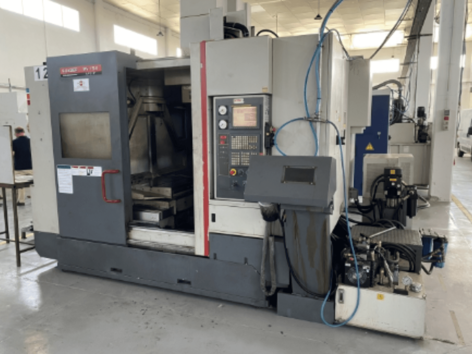 Centre d'usinage vertical Quaser MV154APC-912, vue de face montrant le panneau de commande, la porte ouverte et les composants de la machine.