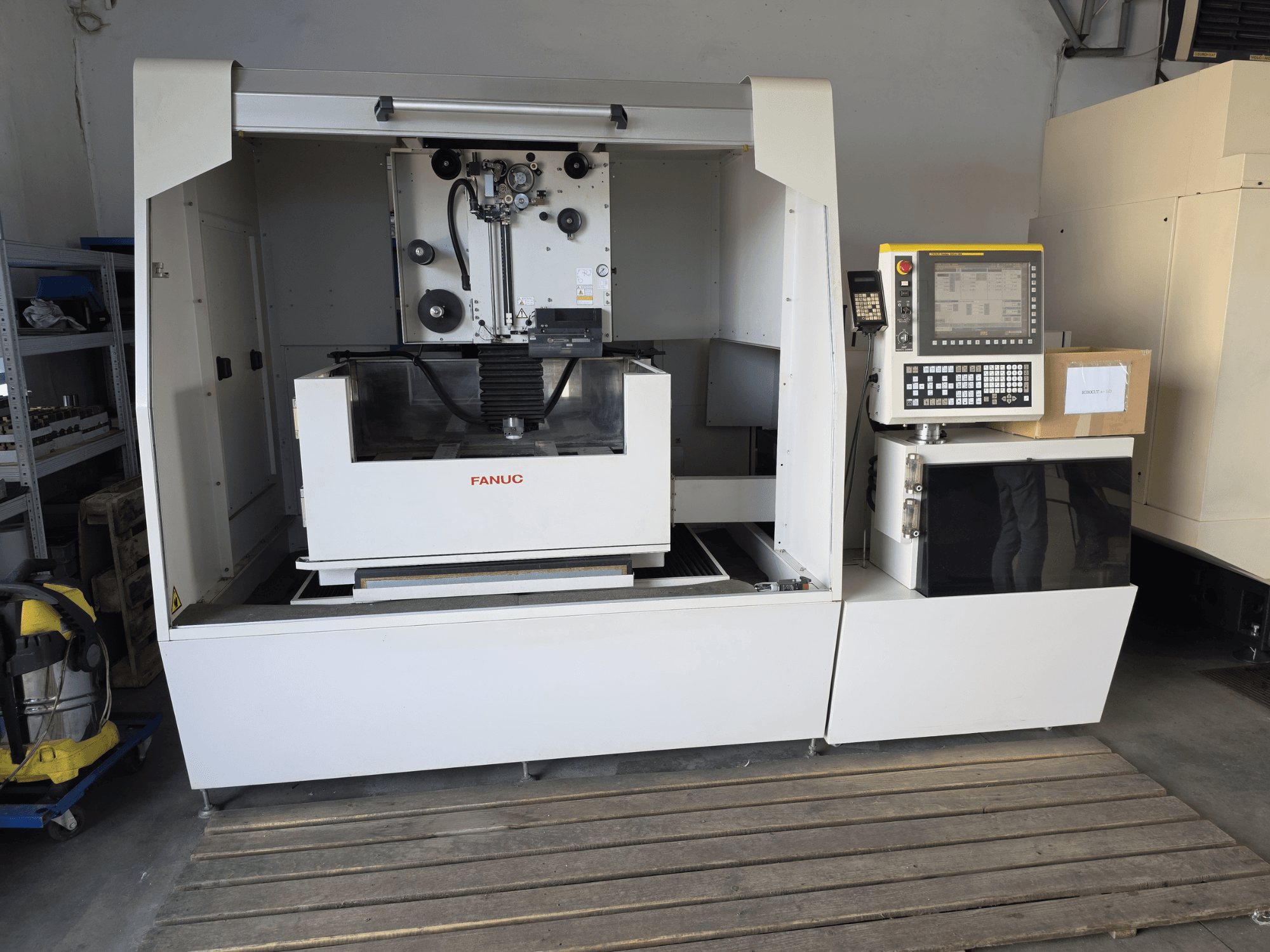 Machine d'électroérosion à fil FANUC ROBOCUT alpha-1iD, vue de face montrant le panneau de commande, la zone de travail et sa conception compacte dans un atelier.