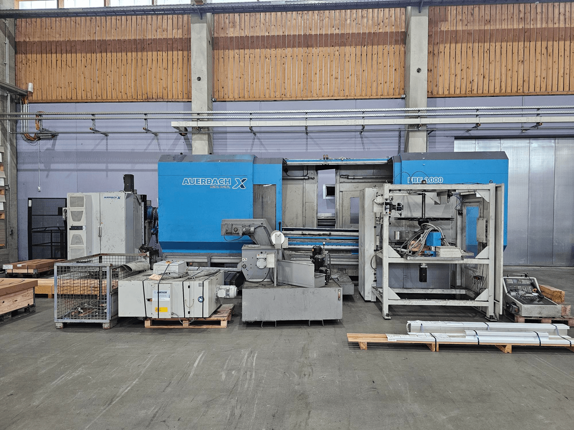 Machine Auerbach X LBF-3000 en usine, vue de côté, avec des composants gris et bleus et un panneau de commande visible.