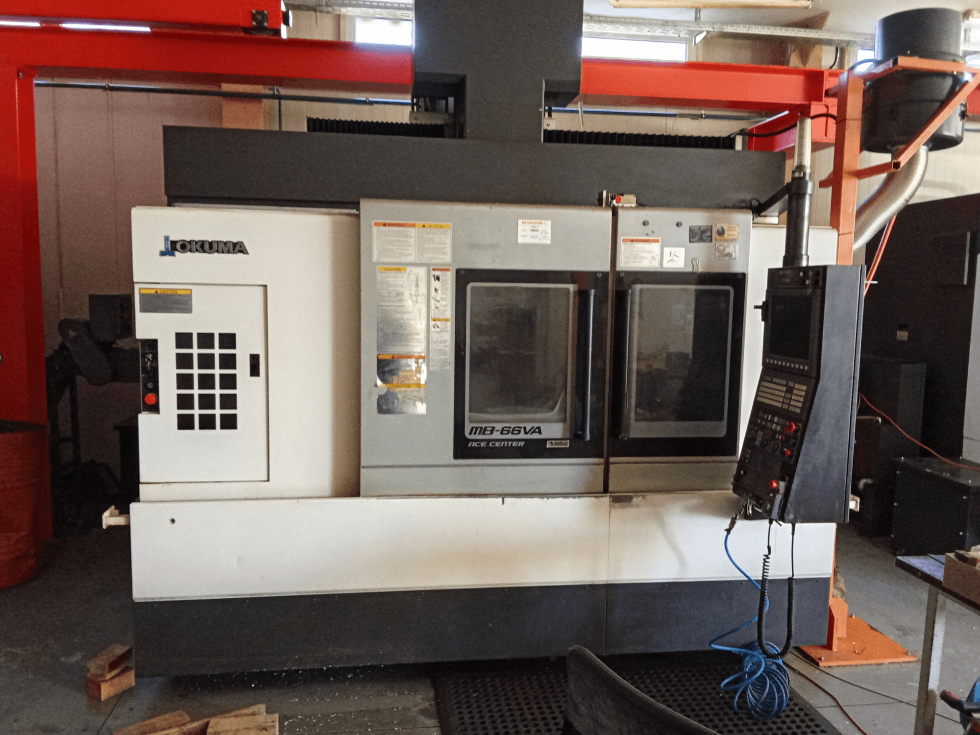 Centre d'usinage vertical Okuma MB-66VA, vue de face montrant le panneau de commande et les deux fenêtres d'accès à l'outillage.