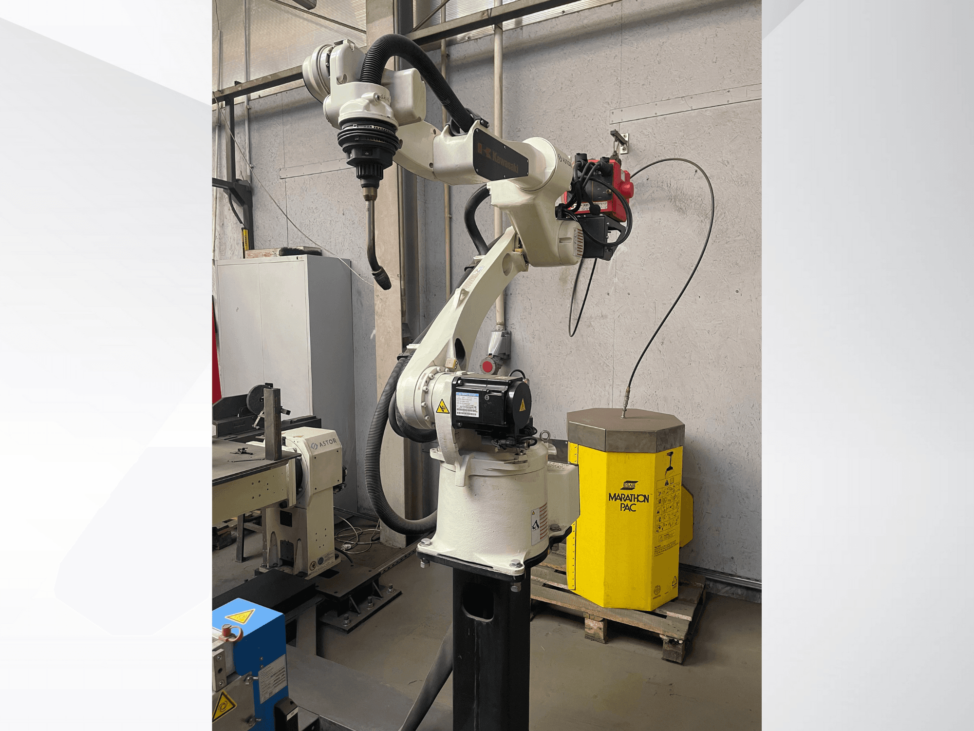 Bras robotisé Kawasaki vu de côté, avec un porte-outil monté, et une unité de puissance jaune en arrière-plan.