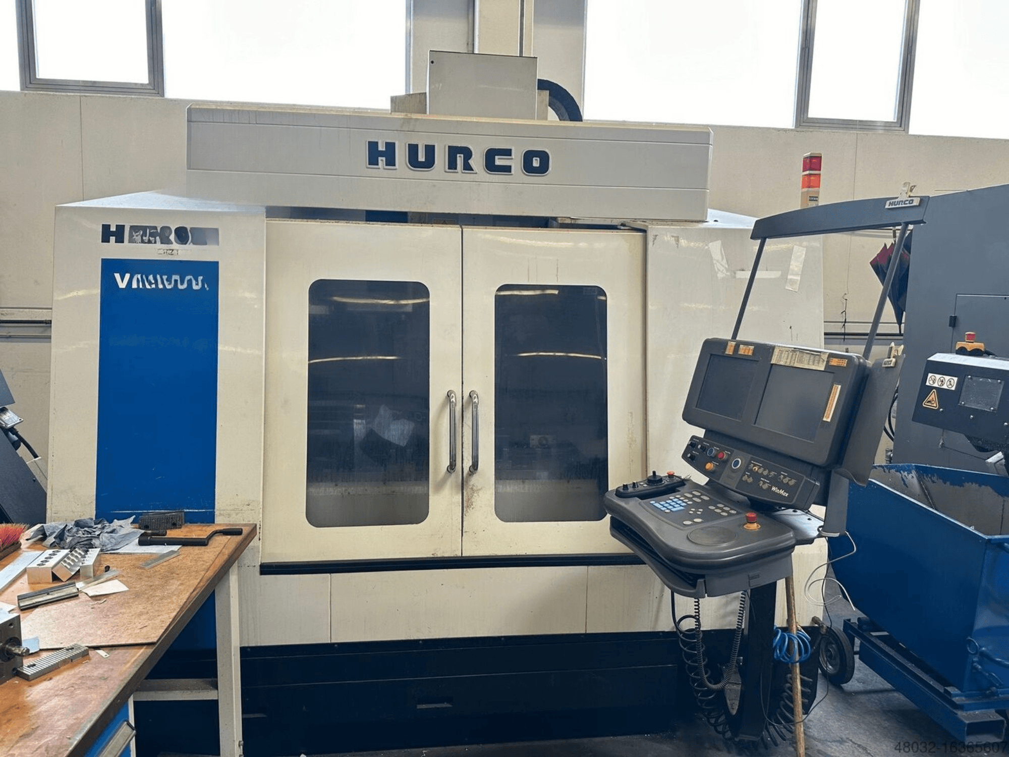 Centre d'usinage vertical Hurco VMX42t, doté d'un panneau de commande et de grandes fenêtres de visualisation, photographié dans un atelier.
