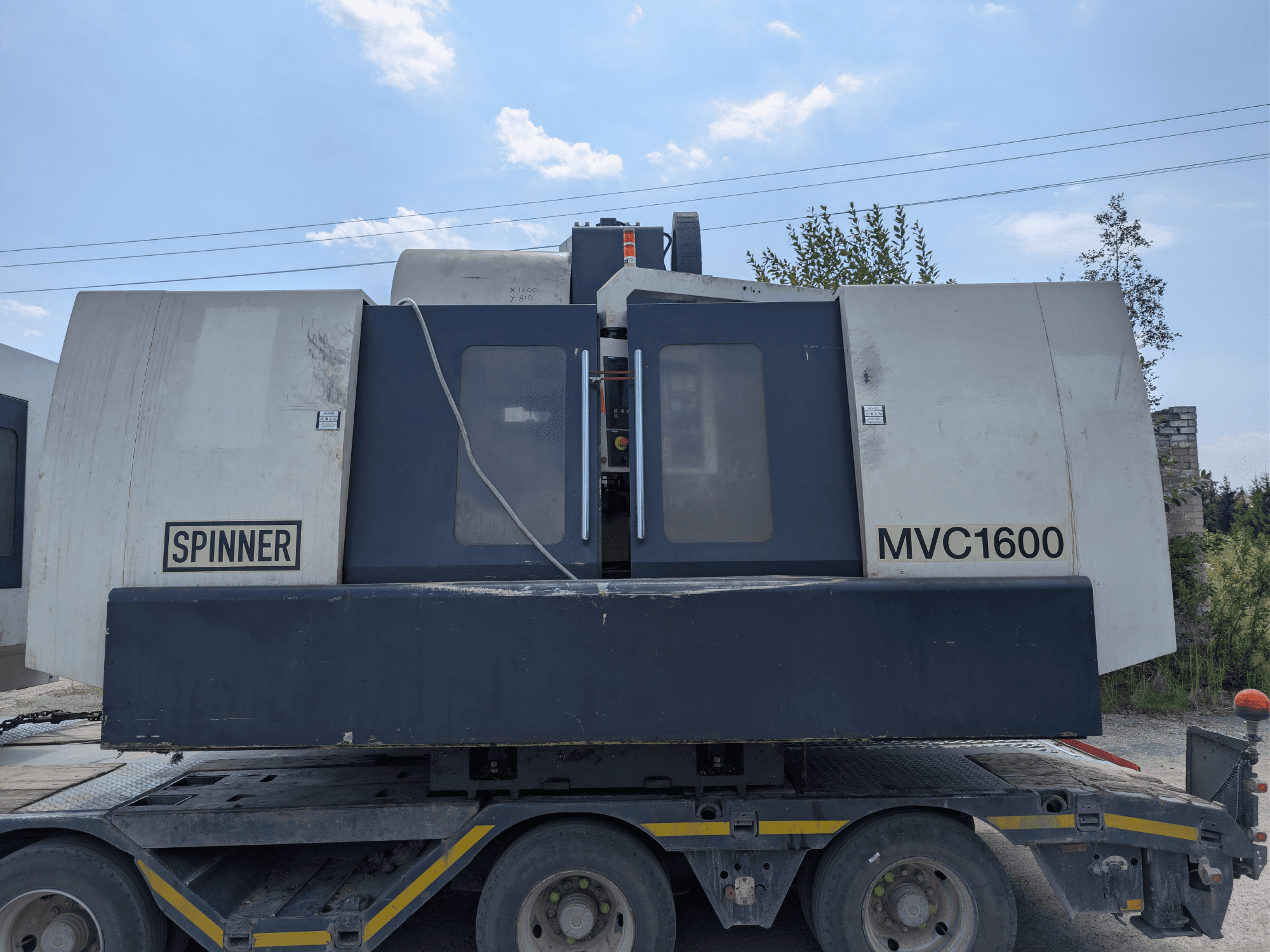 Centre d'usinage vertical SPINNER MVC 1600, vue de face sur un camion, mettant en avant le logo de la marque et la grande zone d'usinage.