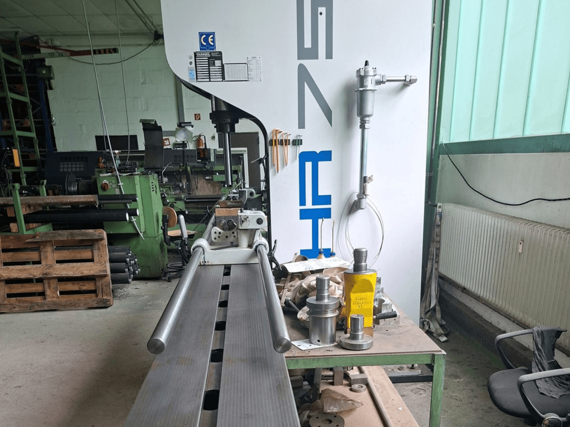 Presse à métaux Dunkes HR75 dans un atelier, vue de profil montrant l'appareil et les outils disposés autour sur la table.