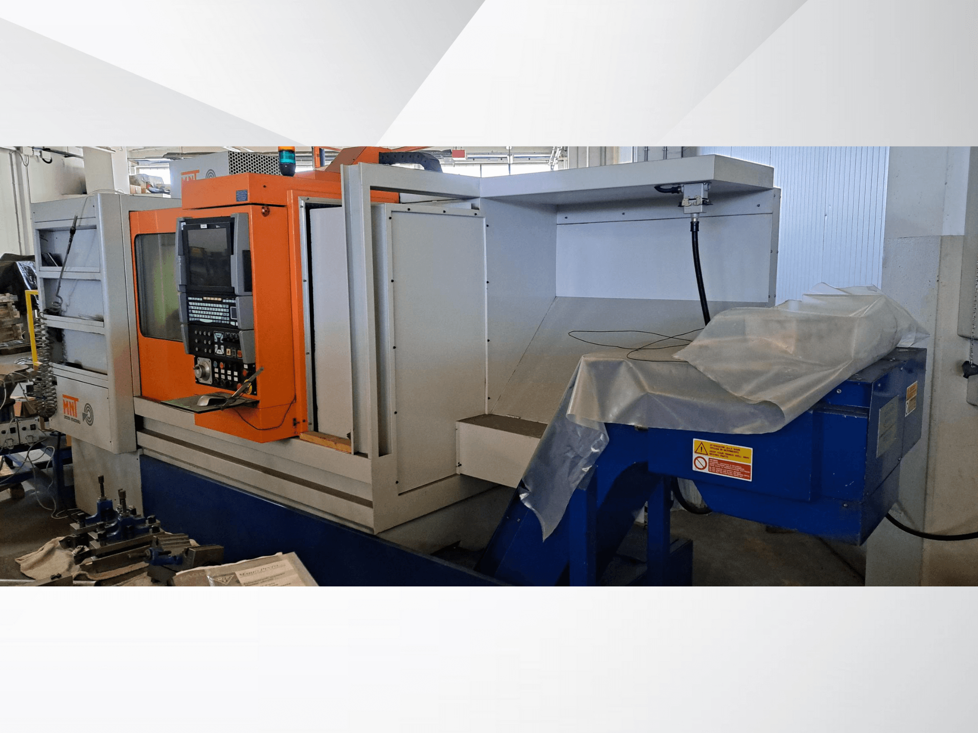 Machine CNC MNT, vue de face, dotée d'un panneau de commande orange, d'une grande zone d'usinage et d'une unité d'élimination des copeaux bleus.