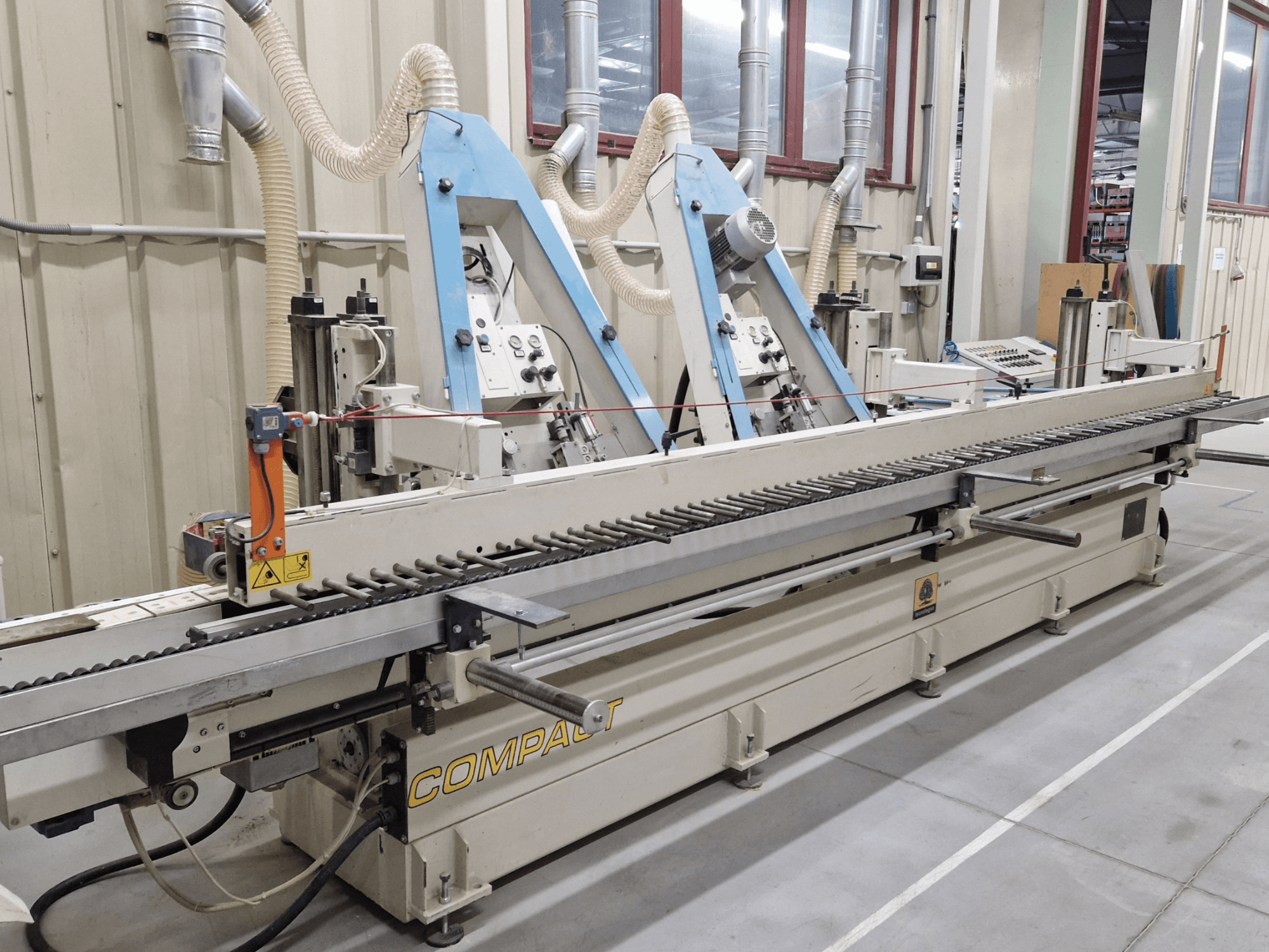 Ponceuse à bande TECNOLEGNO COMPACT 52 dans un atelier, montrant le panneau de commande et le mécanisme de la bande abrasive en vue latérale.