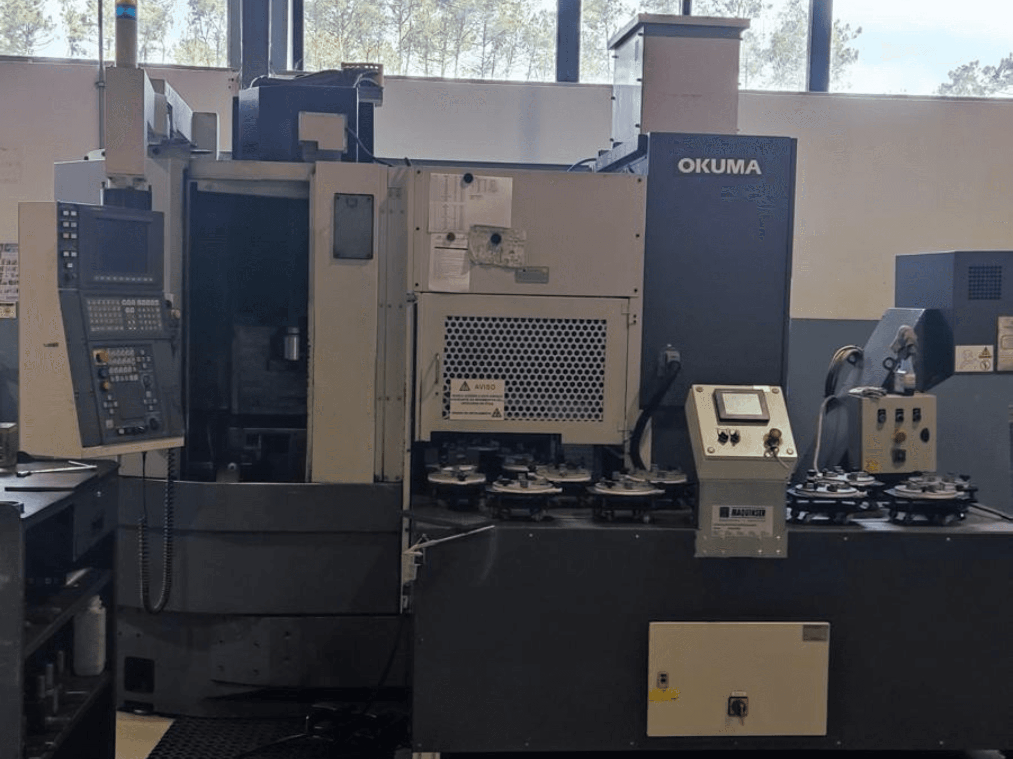Tour vertical LVT300 d'Okuma vu de face, avec le panneau de commande, les porte-outils et la zone d'usinage.