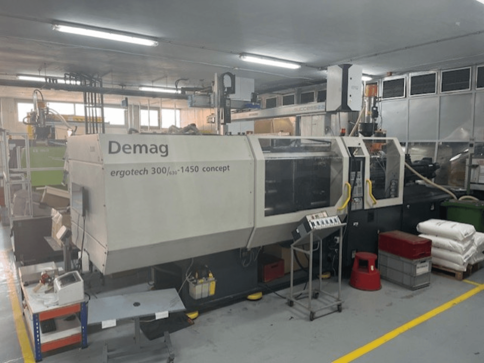 Machine de moulage par injection hydraulique Demag ERGOTECH CONCEPT 3000-1450, vue de face, avec commandes opérationnelles et matériaux à proximité.
