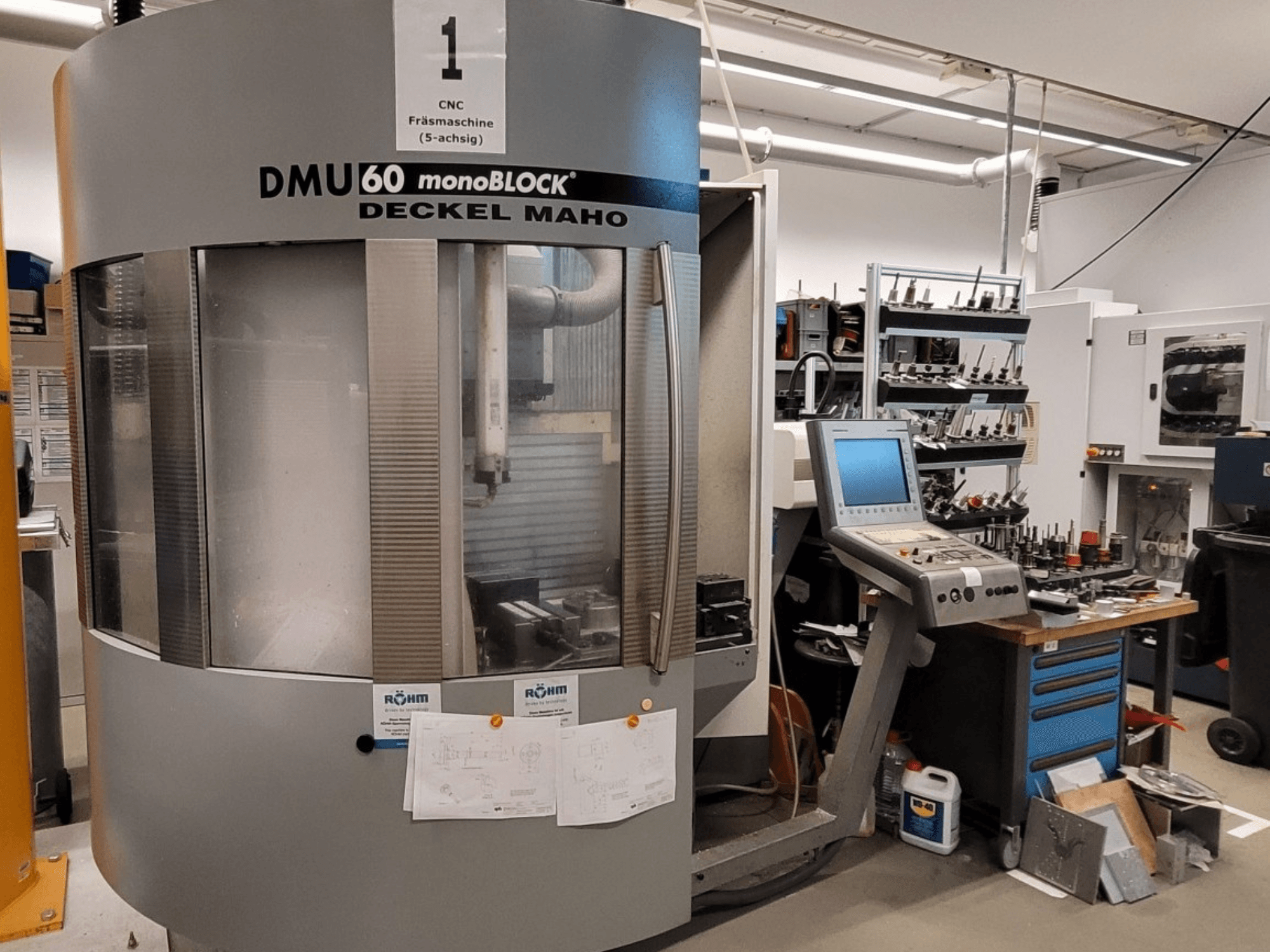 Fraiseuse CNC DECKEL MAHO DMU 60 monoBLOCK en vue frontale, montrant le panneau de commande et le magasin d'outils à côté.