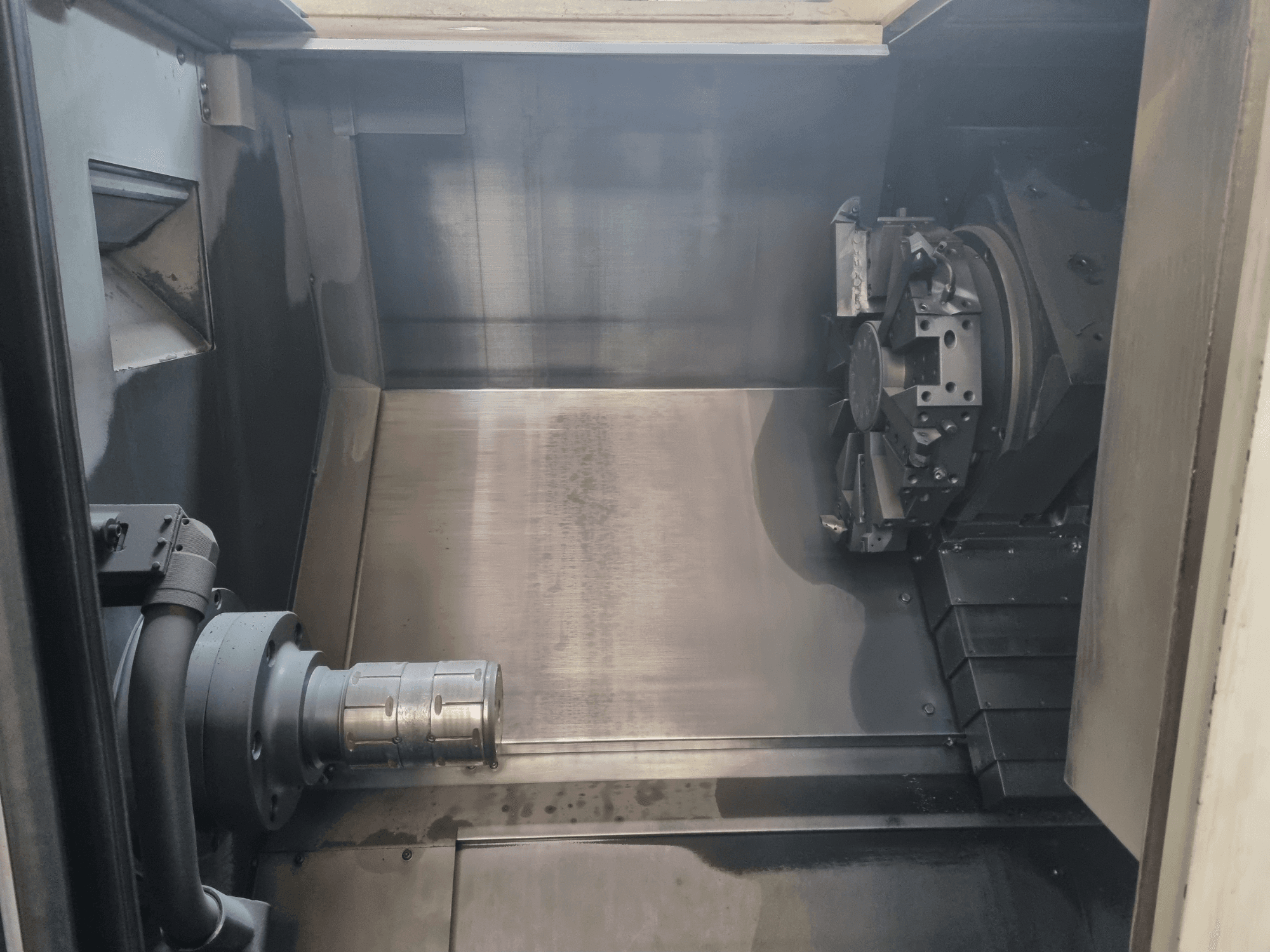 Vue intérieure d'une machine CNC montrant une zone de travail en métal, un porte-outil et un mandrin ; met l'accent sur l'ingénierie de précision.