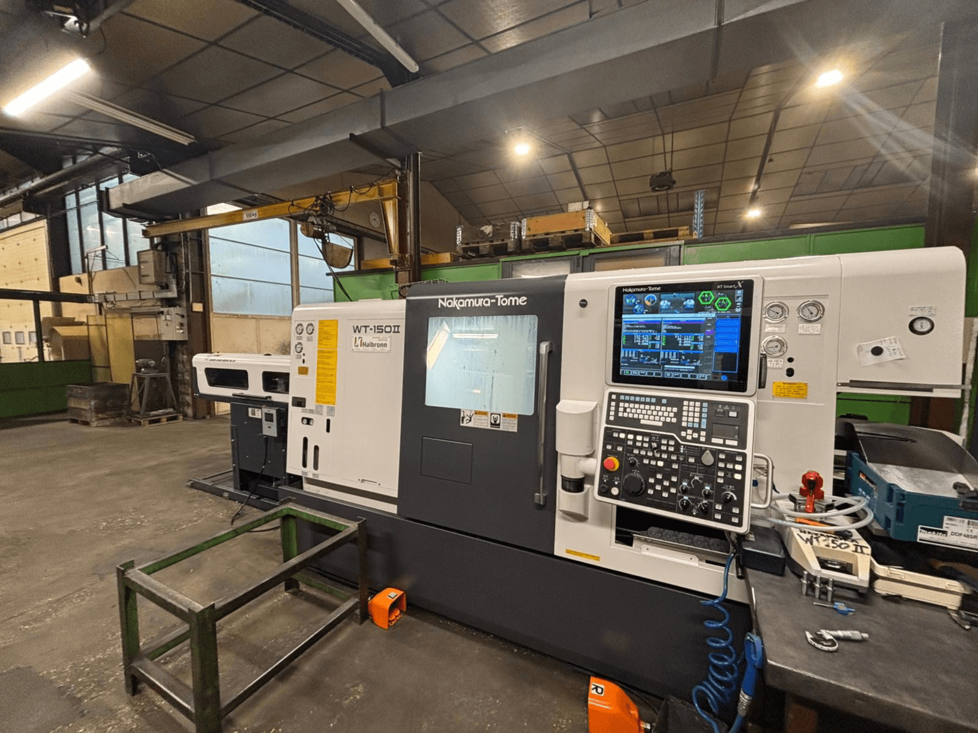 Machine Nakamura-Tome WT-150II, vue de face, avec panneau de commande et outils visibles sur un établi dans un atelier.