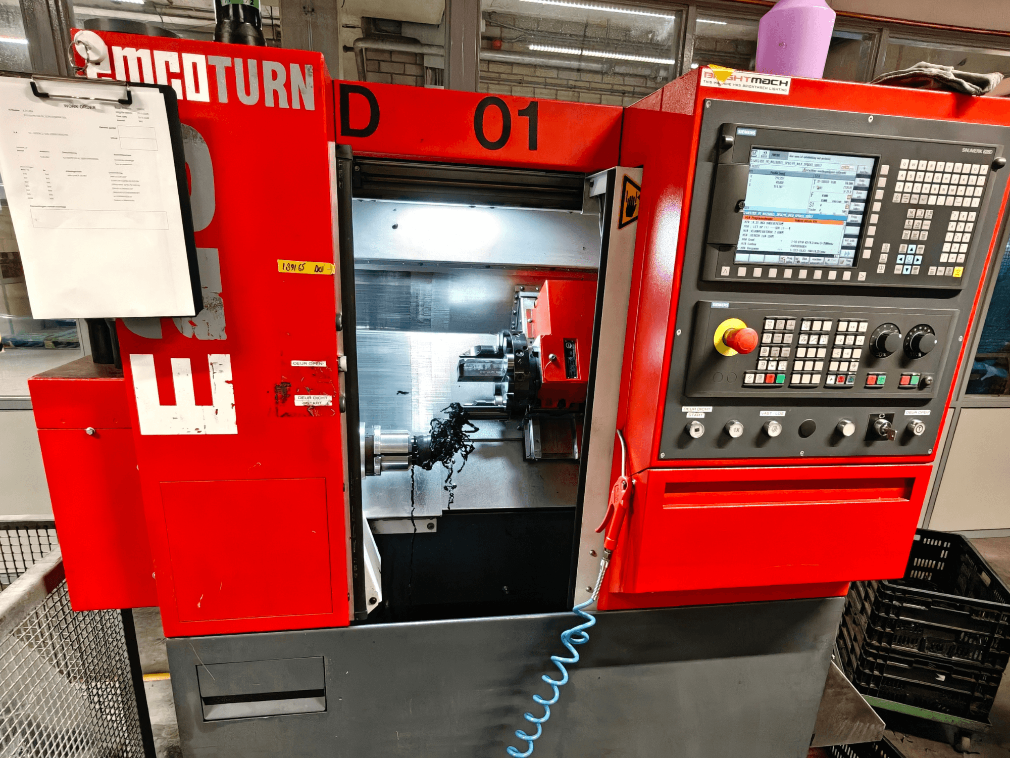 Vue de face du tour horizontal EMCO TURN E25, avec ses commandes, son porte-outil et sa zone de travail avec des copeaux.