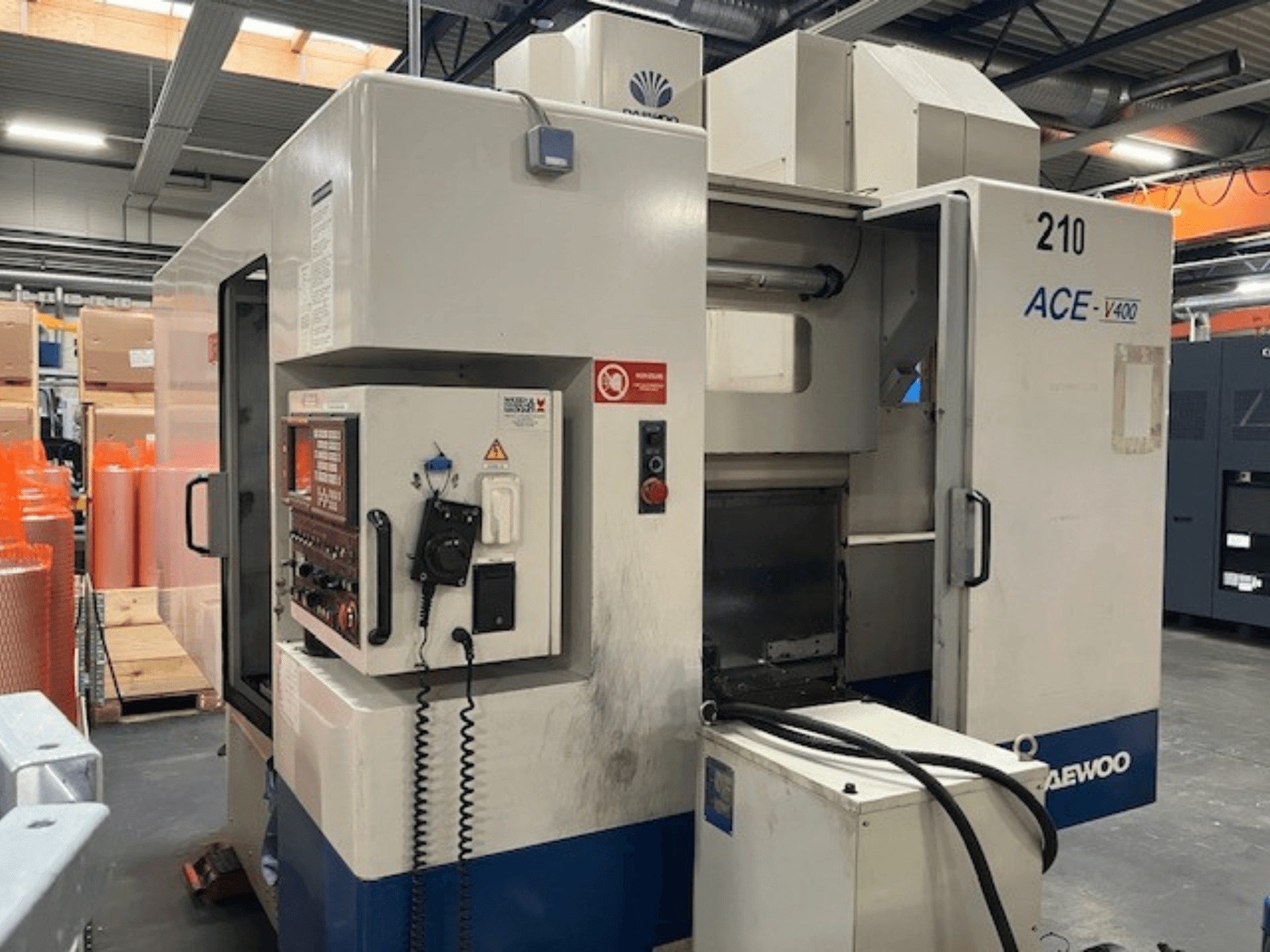 Machine CNC Daewoo ACE-V400 vue de côté, avec panneau de commande, réservoir de liquide de refroidissement et zone de travail ouverte.