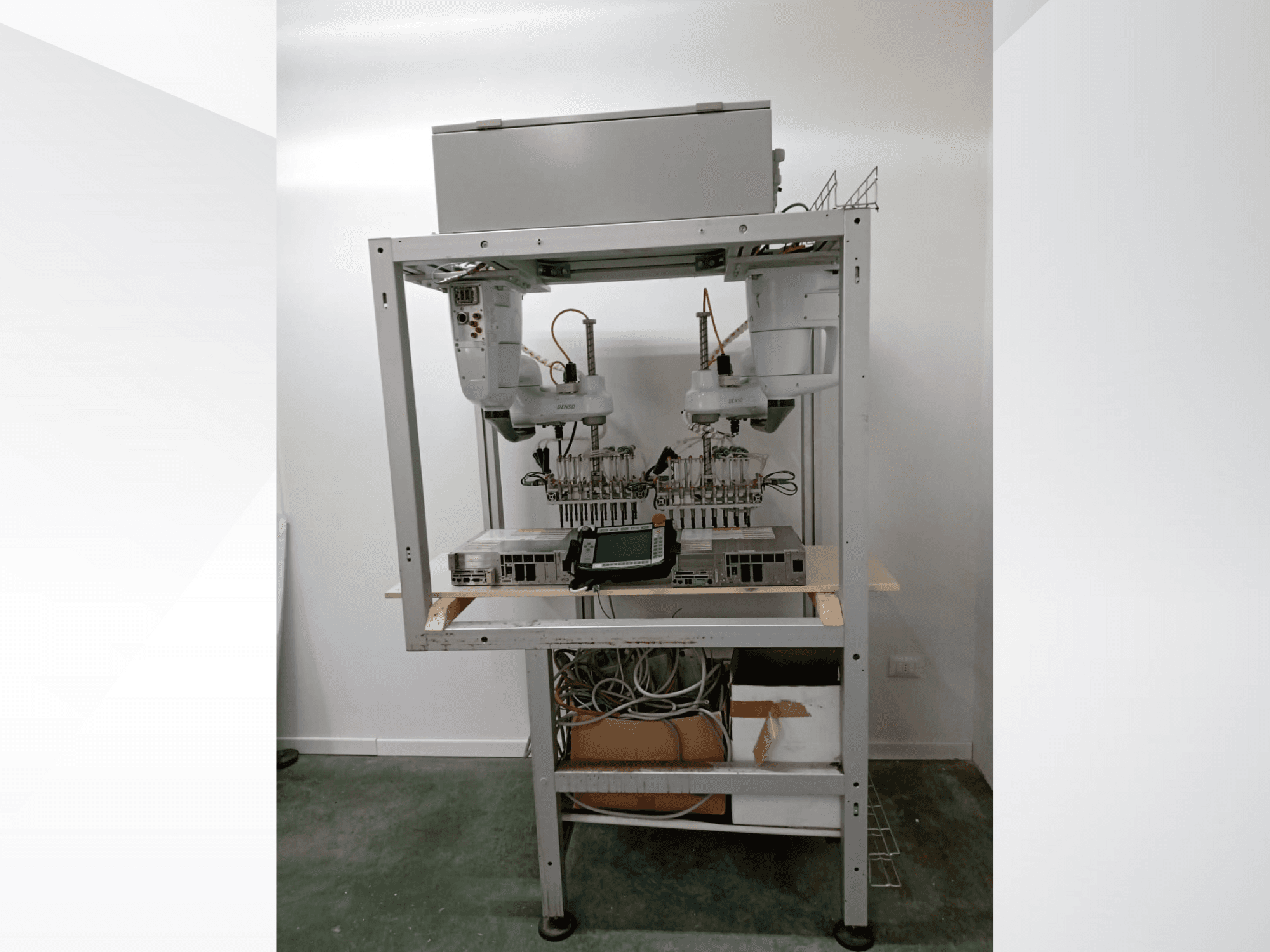 Poste de travail robotisé automatisé avec deux bras, une unité d'affichage et des composants électroniques sur un cadre métallique, vue de face, installation de technologie avancée.