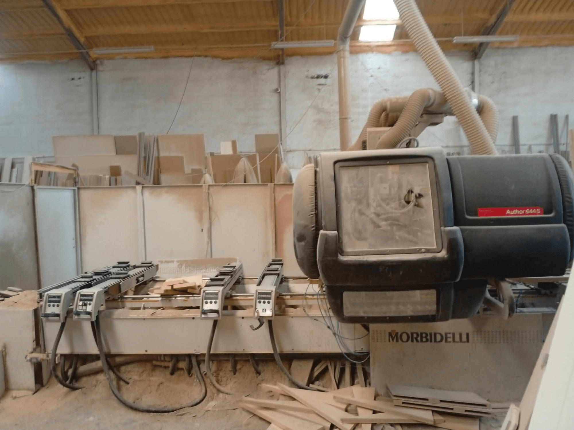 Centre d'usinage CNC MORBIDELLI A644S FTP 41 PC exposé dans un atelier, vu de face, avec de la poussière et des débris de bois.