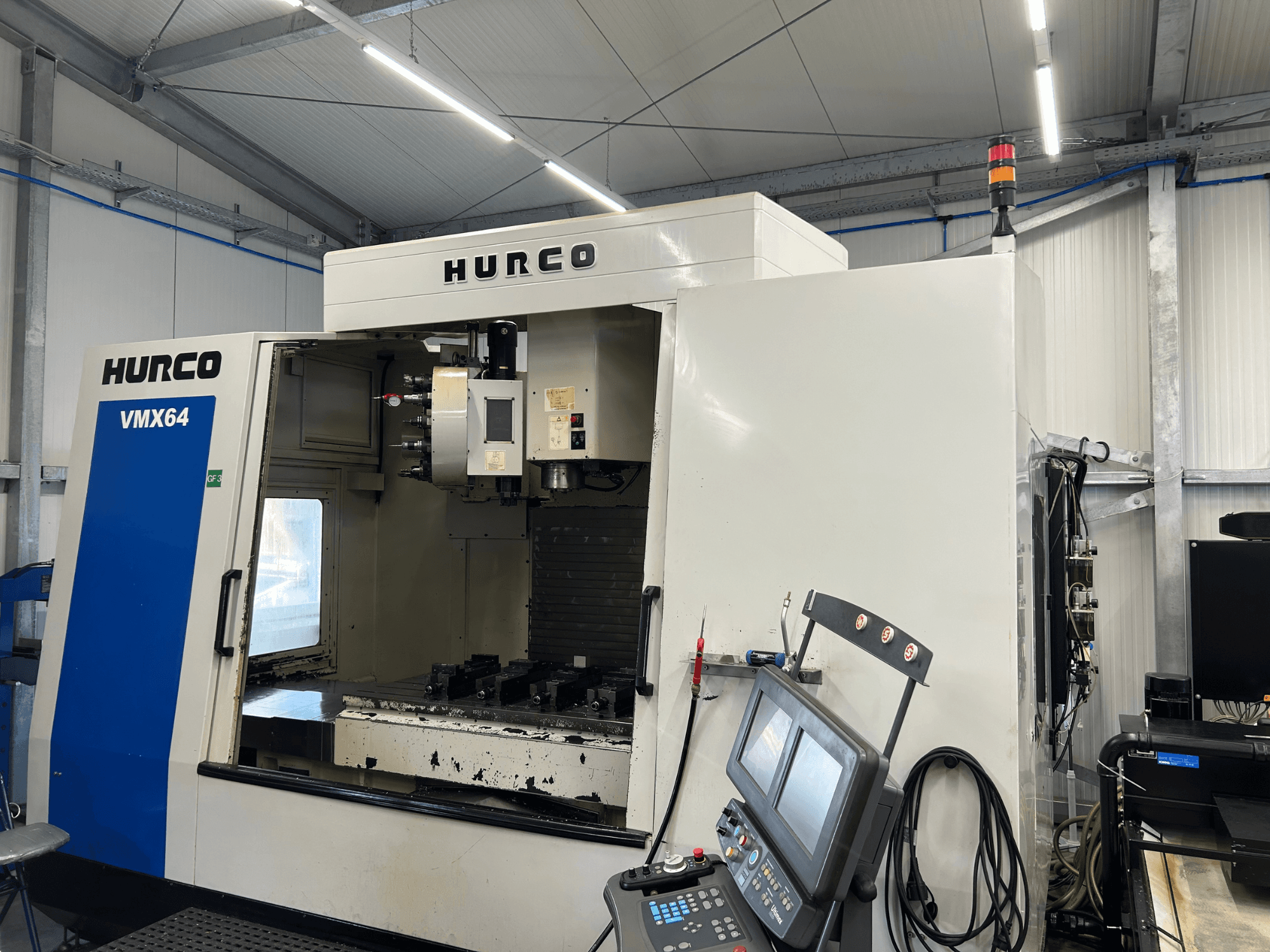 Centre d'usinage vertical Hurco VMX 64, vue de face, mettant en évidence le panneau de commande et l'espace de travail dégagé avec les outils.