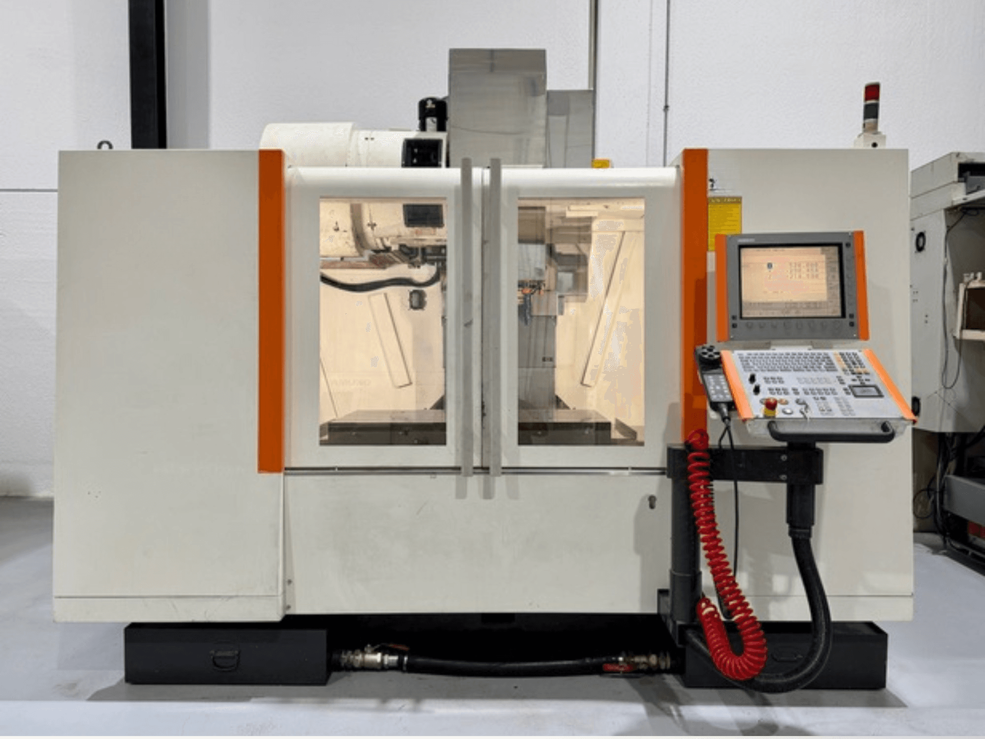 Machine à commande numérique avec accents orange, vue de face. Comprend un panneau de commande et des éléments intérieurs visibles.