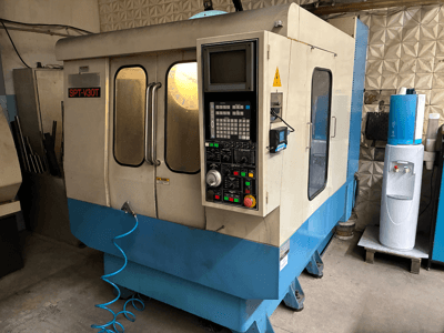 Machine CNC SPT-V30T en bleu et blanc, vue de face montrant le panneau de commande, les portes et le tuyau d'air. Parfaite pour l'usinage de précision.