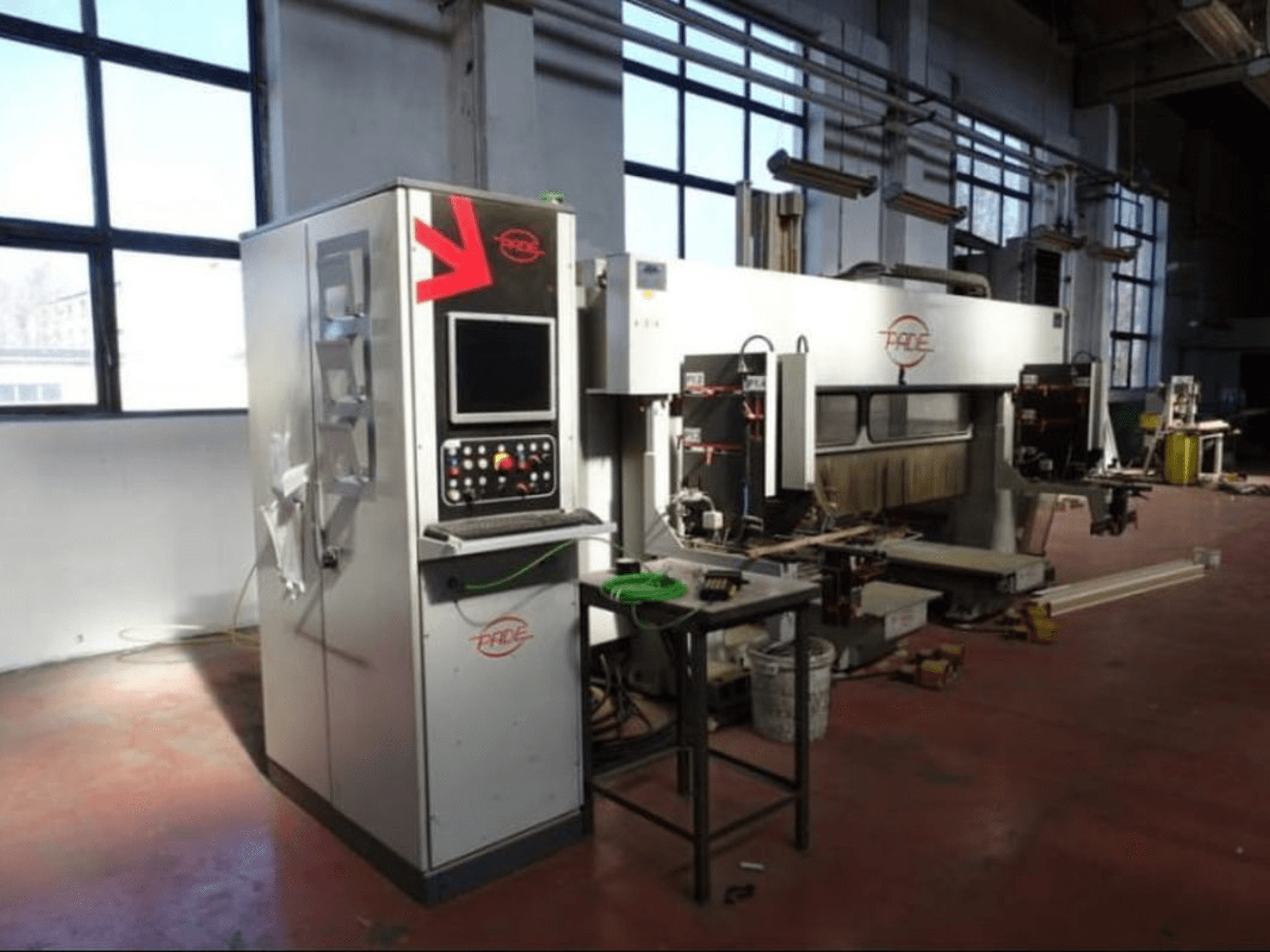 Centre d'usinage CNC pour le bois PADE VELUX, vue de face avec le panneau de commande, les outils visibles et des pièces de bois dans un atelier bien éclairé.