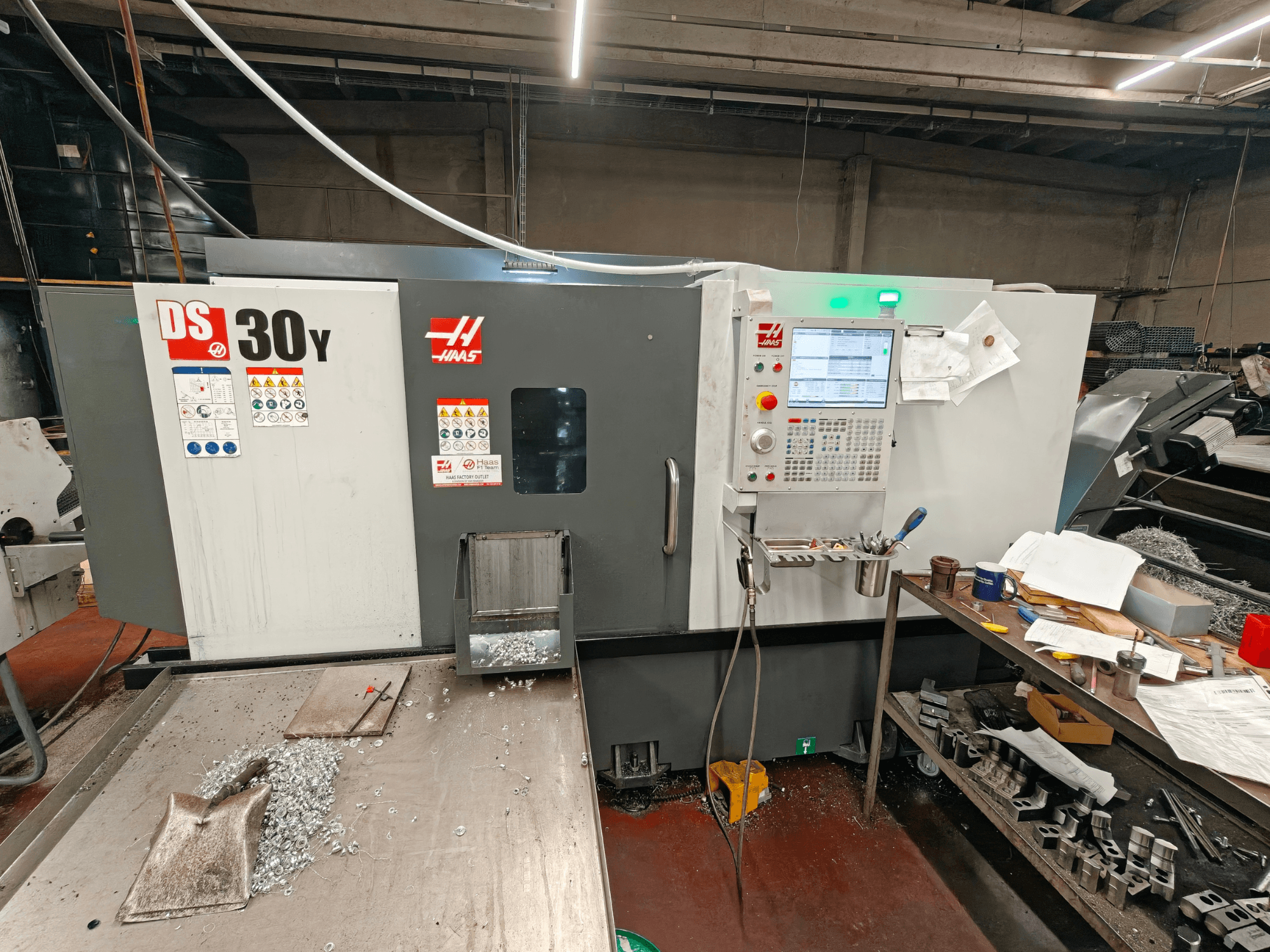Tour horizontal HAAS DS30Y dans un atelier, vue de face montrant le panneau de commande et des copeaux de métal sur la surface.
