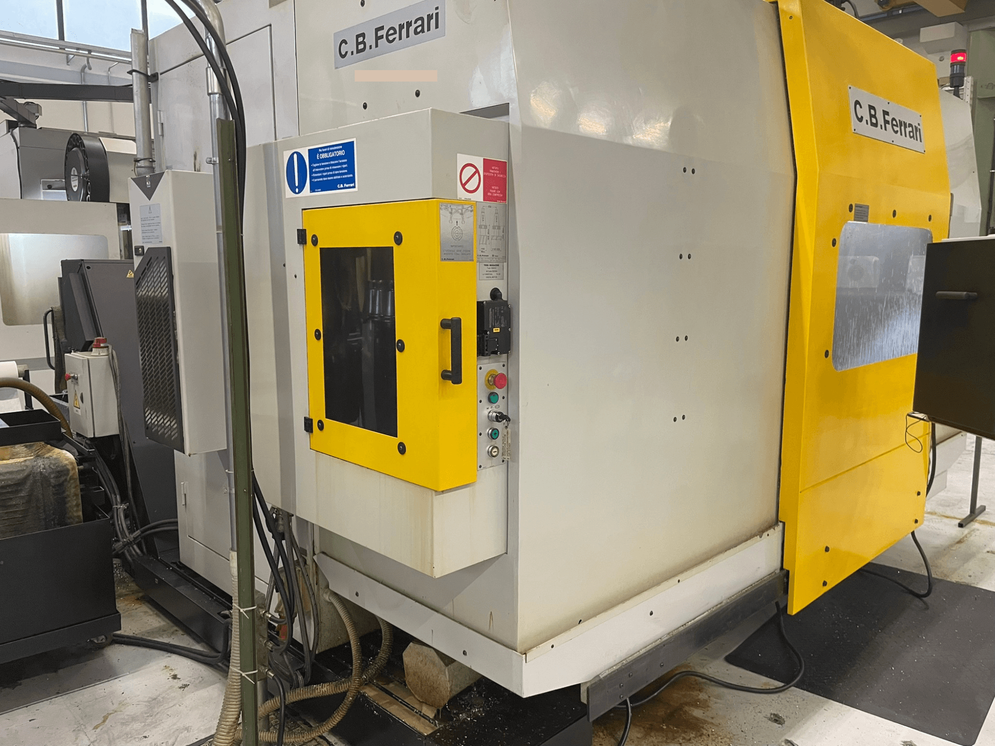 Machine industrielle C.B. Ferrari, vue de face ; porte jaune, panneau de commande et composants d'usinage visibles.