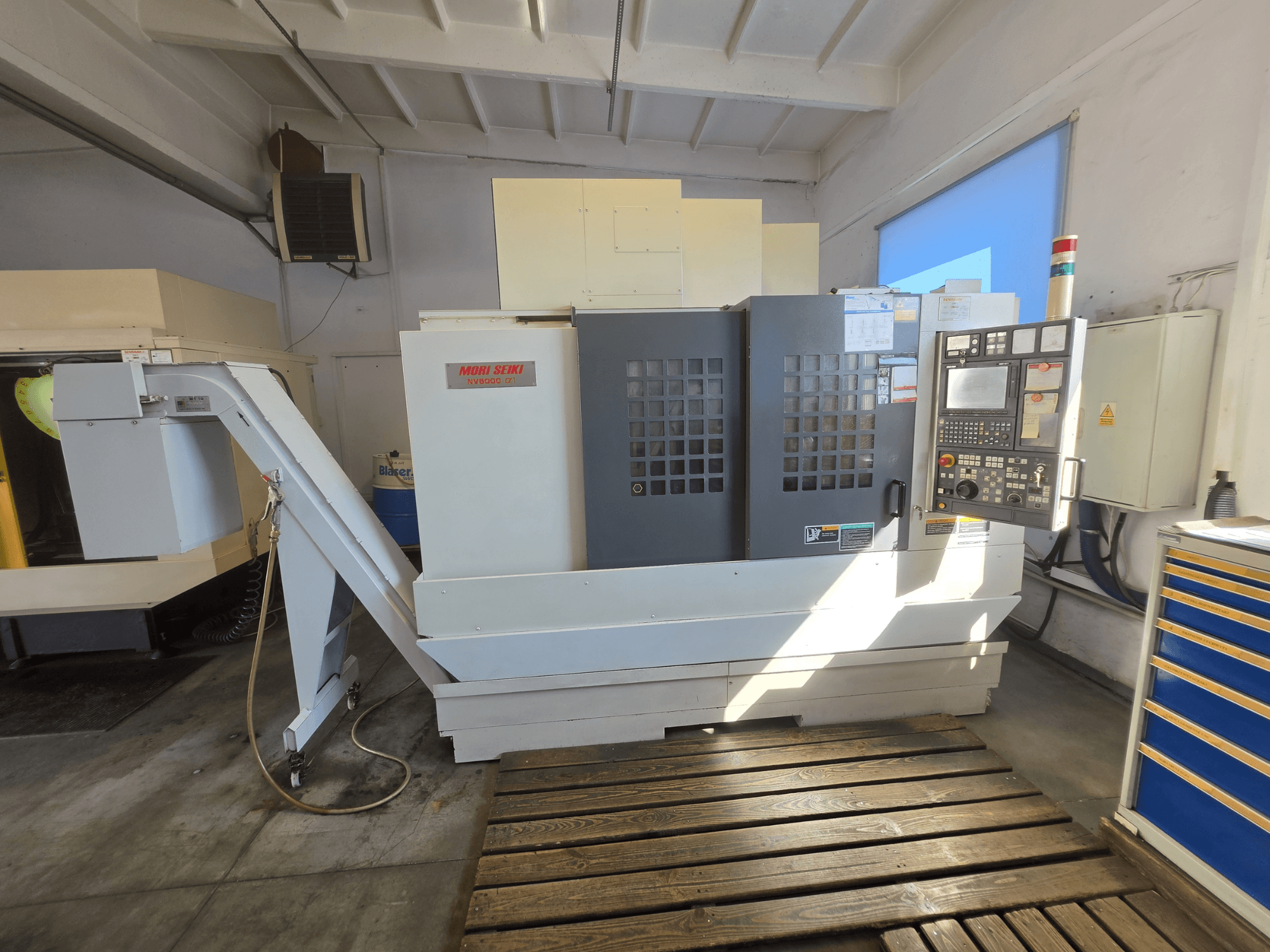 Centre d'usinage vertical MORI SEIKI NV 5000 alpha1, vue de face montrant le panneau de commande et les caractéristiques de la machine dans un atelier.