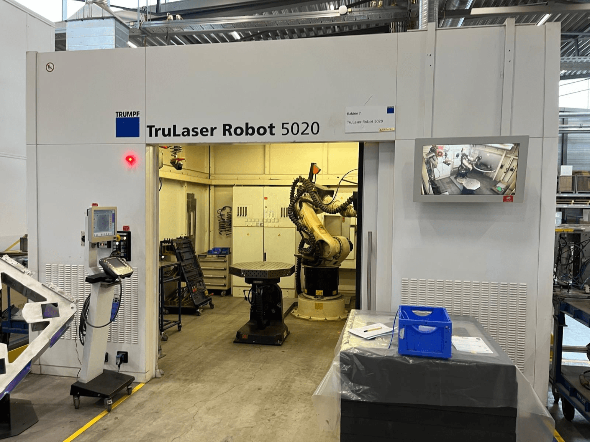 TRUMPF TruLaser Robot 5020 dans un environnement industriel, avec son panneau de commande, son bras robotisé et un écran affichant les opérations en cours.