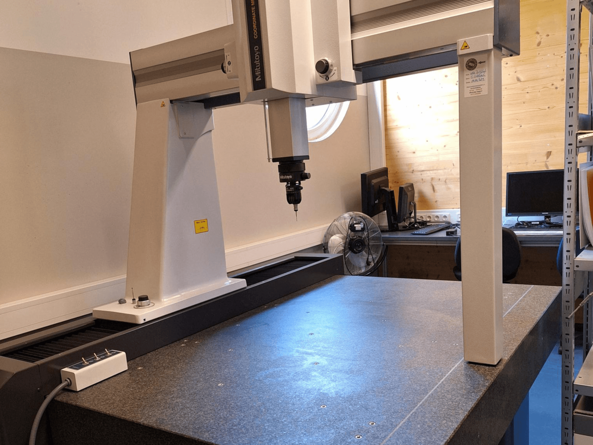 Robot à portique Mitutoyo Crysta-Plus M7106 dans un atelier, vue de face, mettant en évidence la sonde de mesure et la plaque de mesure en granit.