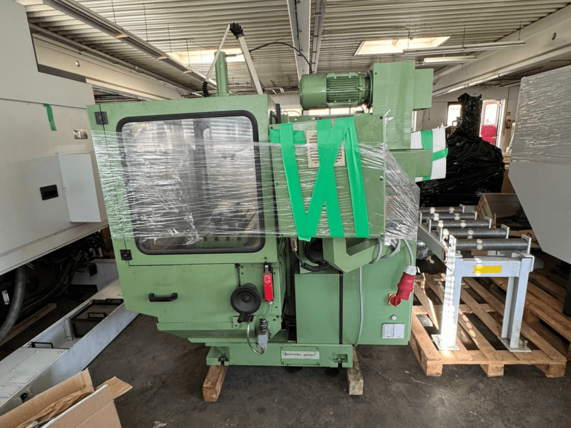 Centre d'usinage vertical KUNZMANN WF 4/3, vu de face, emballé sous film plastique, avec un corps vert et des commandes visibles.