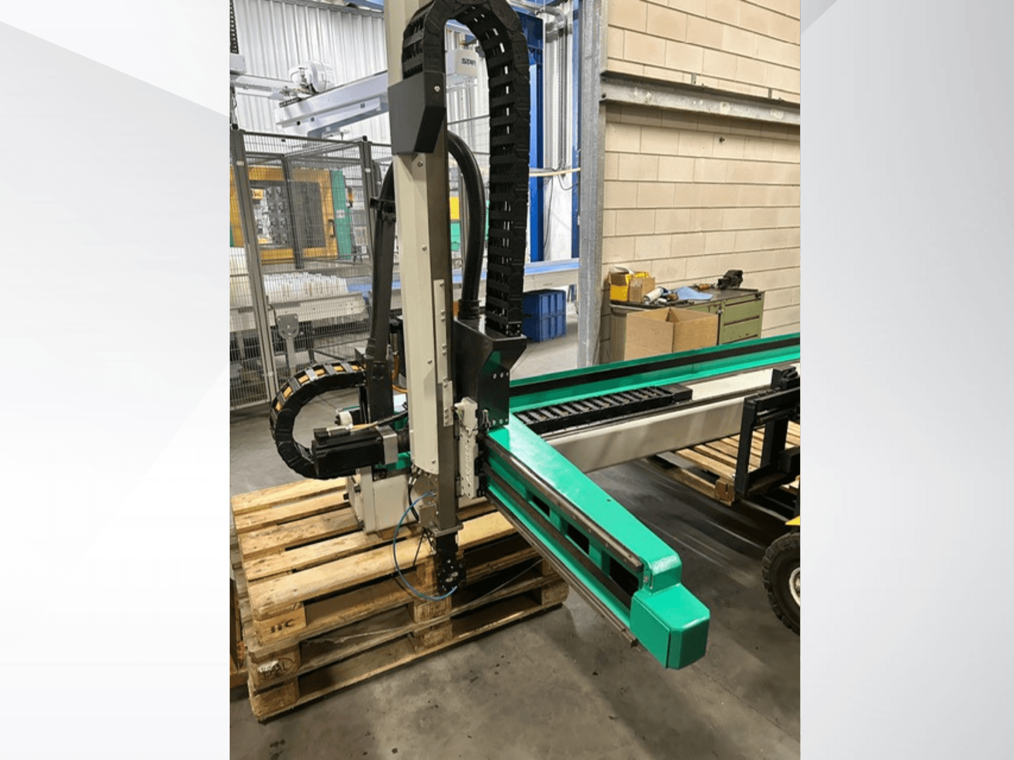Arburg Multilift Select 15kg quer, vue latérale du système de manutention de pièces sur des palettes en bois, montrant le bras robotique et les composants de contrôle.