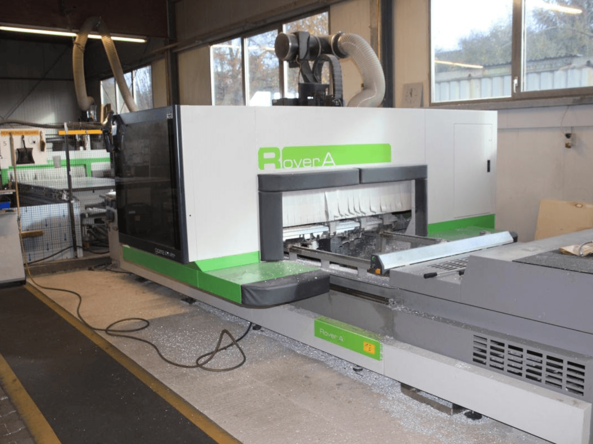 Défonceuse CNC BIESSE Rover A 1232, vue latérale montrant la zone de coupe et le panneau de commande dans un environnement industriel.