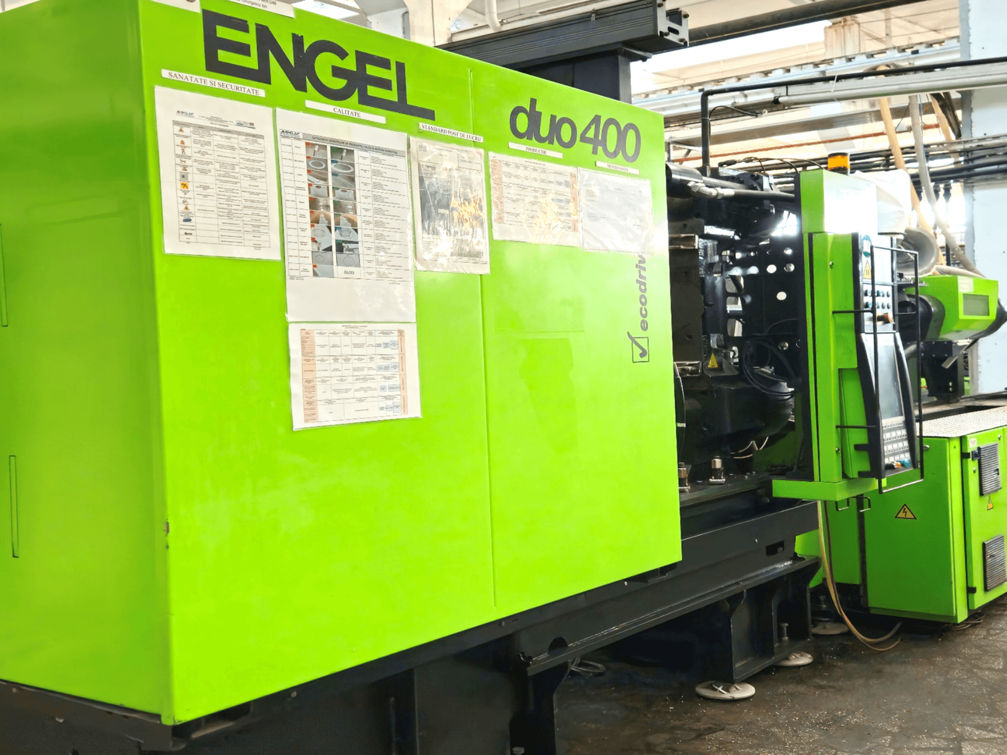 Machine de moulage par injection ENGEL duo 400 verte, vue de face, présentant le panneau de commande et la documentation de sécurité à l'extérieur.